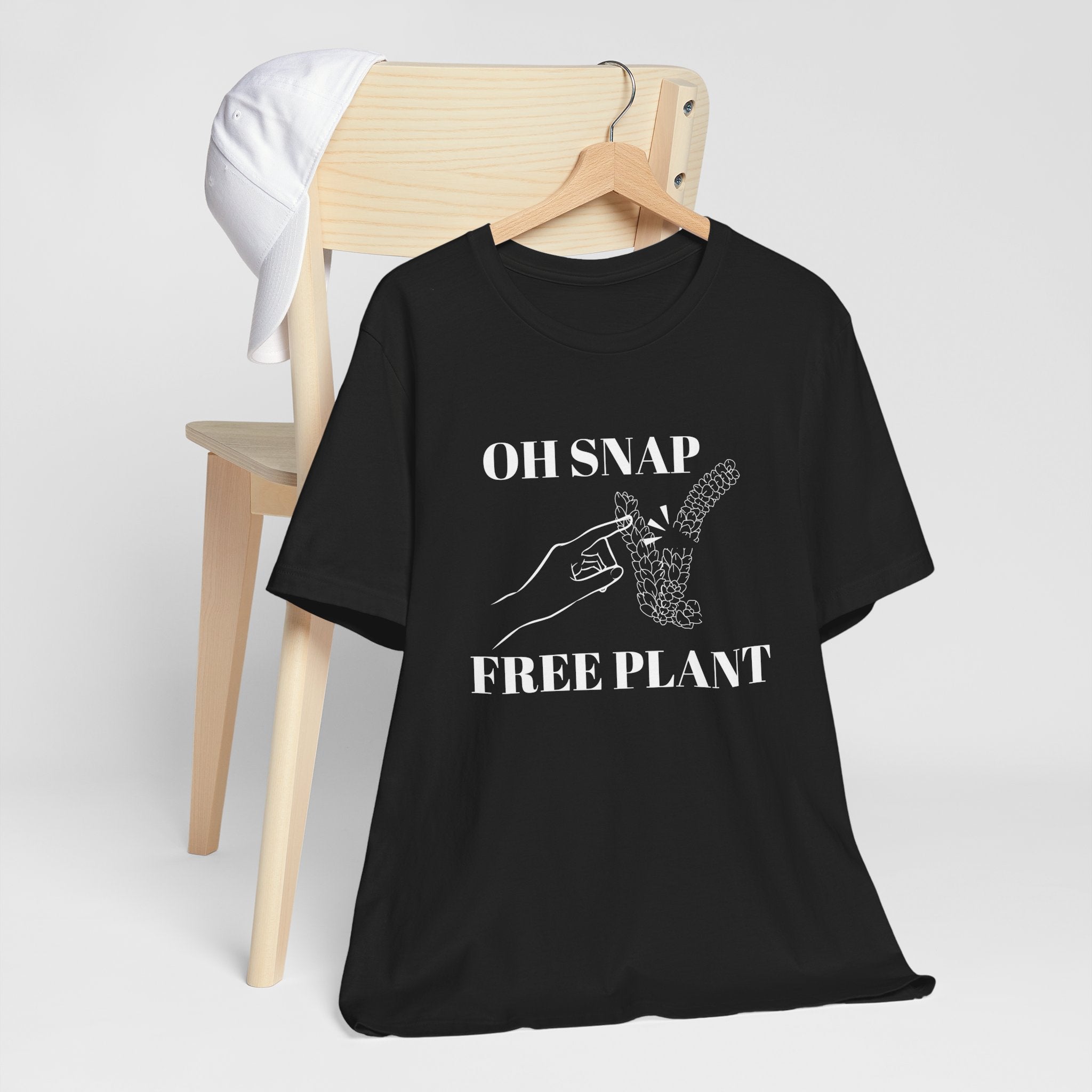 A black colored shirt with text that says "Oh snap" "free plant."  The shirt design also has a burro's tail plant snapped in half and a finger pointing to it. The shirt is an excellent gift for birthdays and Christmas. House plant collectors love this funny t-shirt.