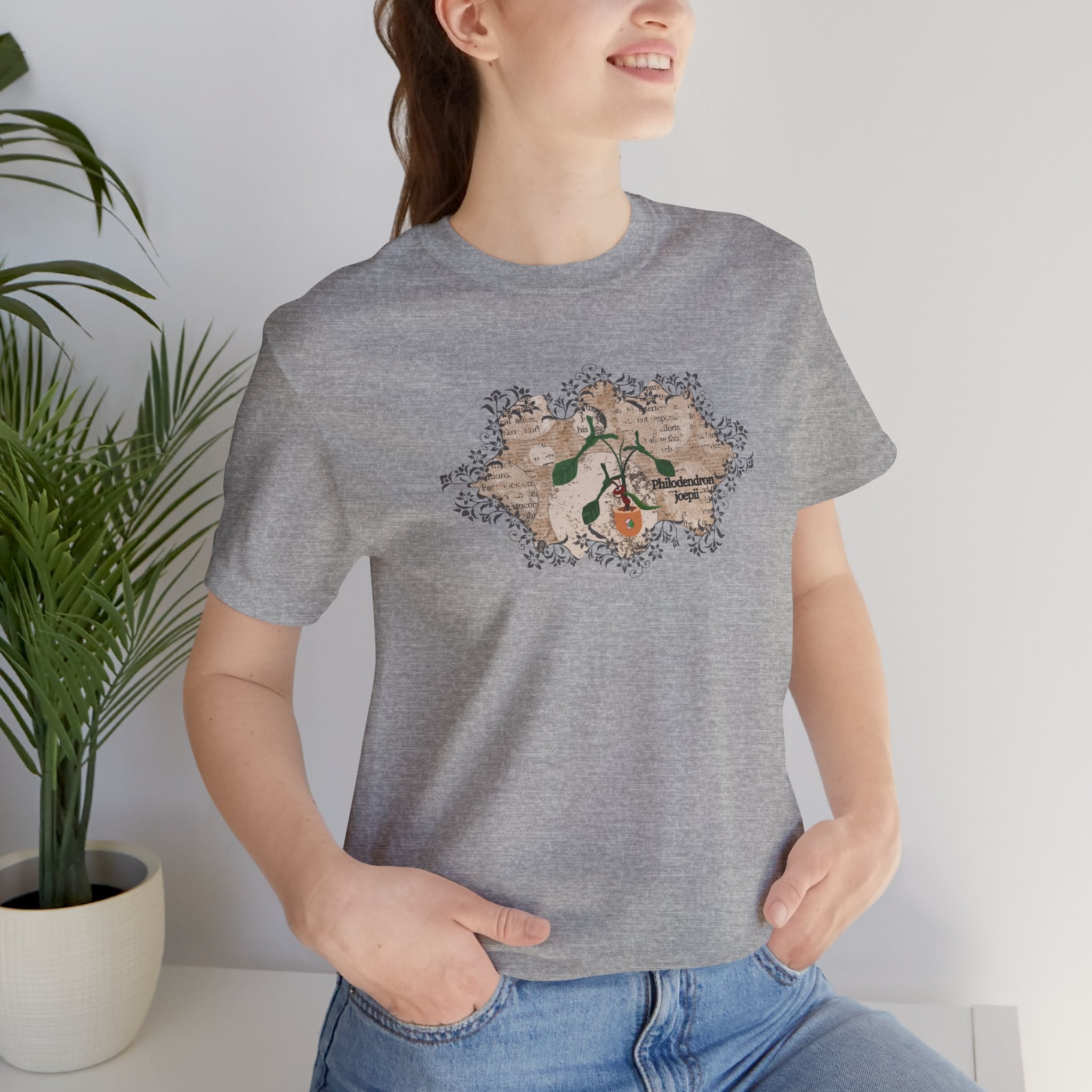 A college student wearing a t-shirt with a philodendron joepii plant design, an ant eating the plant, and the 1pink1 plants logo. Perfect plant t-shirt for plant lovers. Excellent gift for birthdays and Christmas Day.