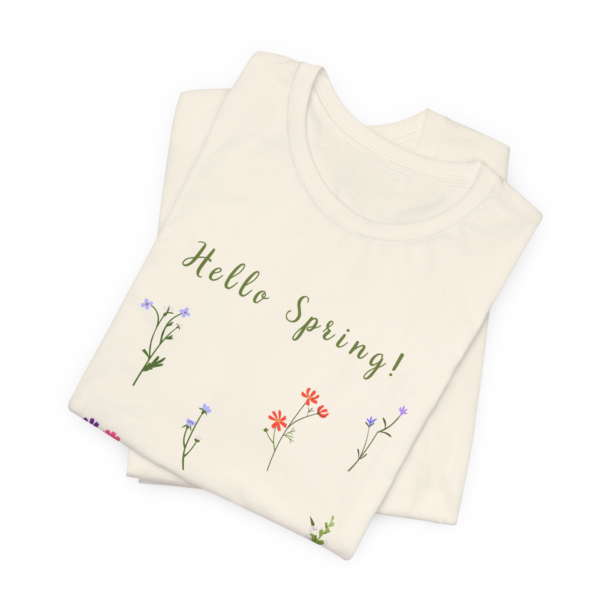 A casual tee shirt with wild flowers and the text that says "Hello Spring!" The t-shirt is available in a natural color.