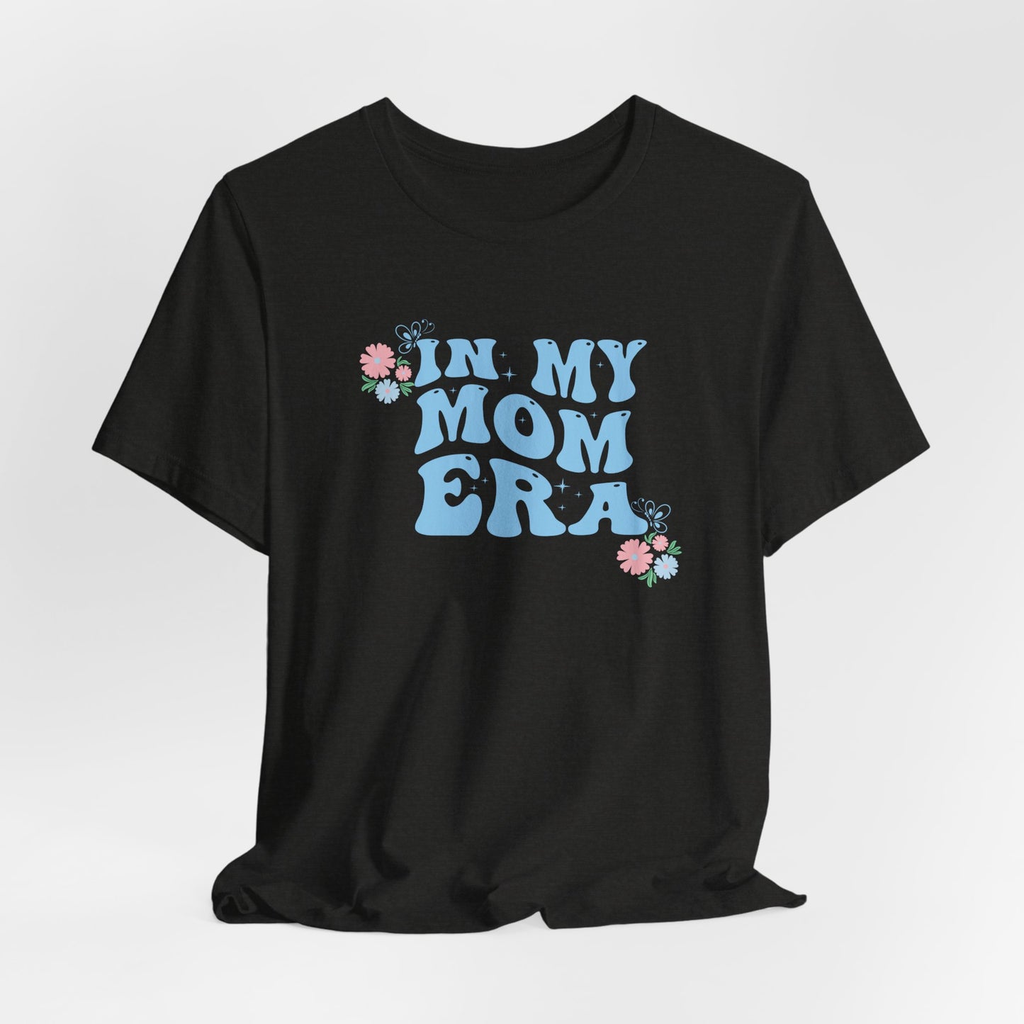 a black heather color graphic tee with the words "In my mom era" printed in blue.