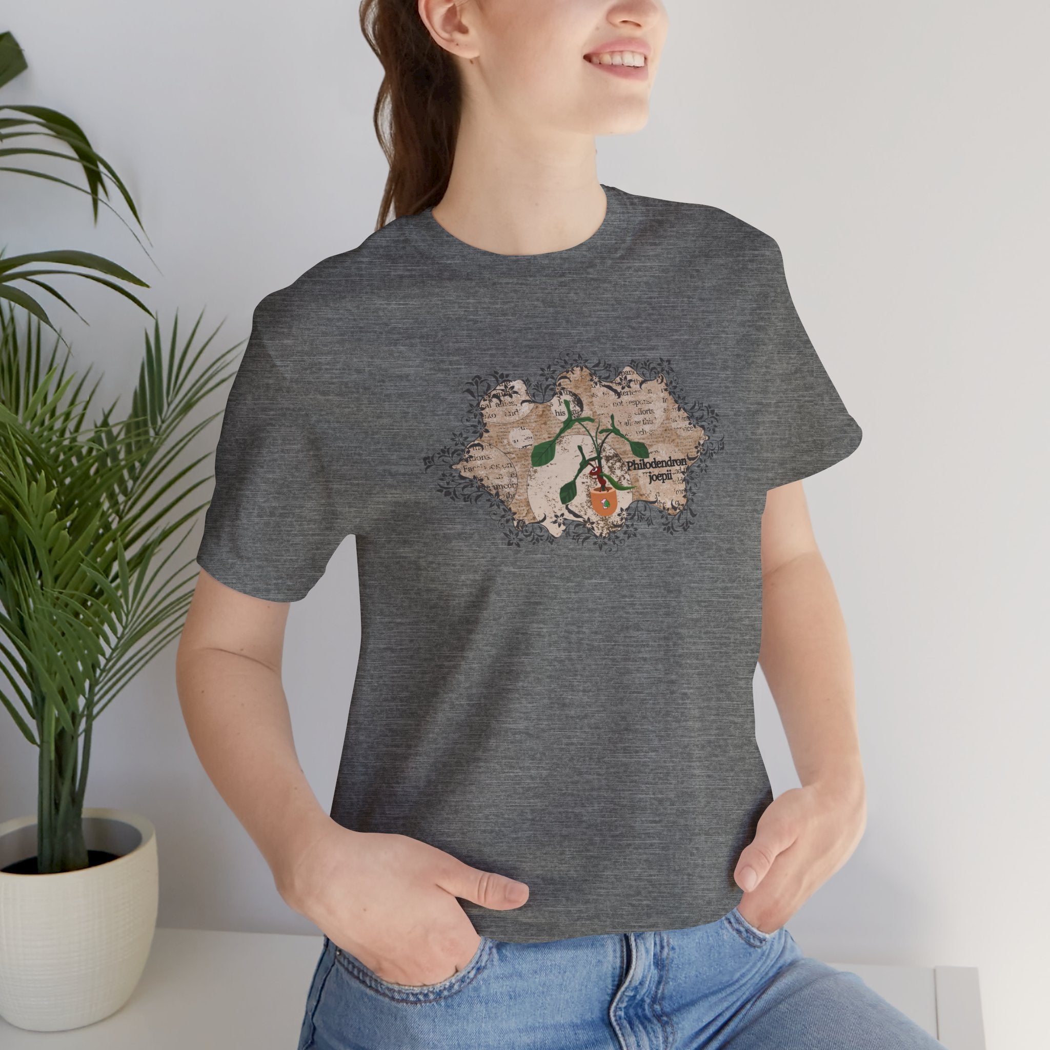 A woman wearing a plant t-shirt with a philodendron plant design. The philodendron joepii is printed on the t-shirt along with an ant eating the plant leaves. The shirt makes an excellent Christmas gift or birthday gift.