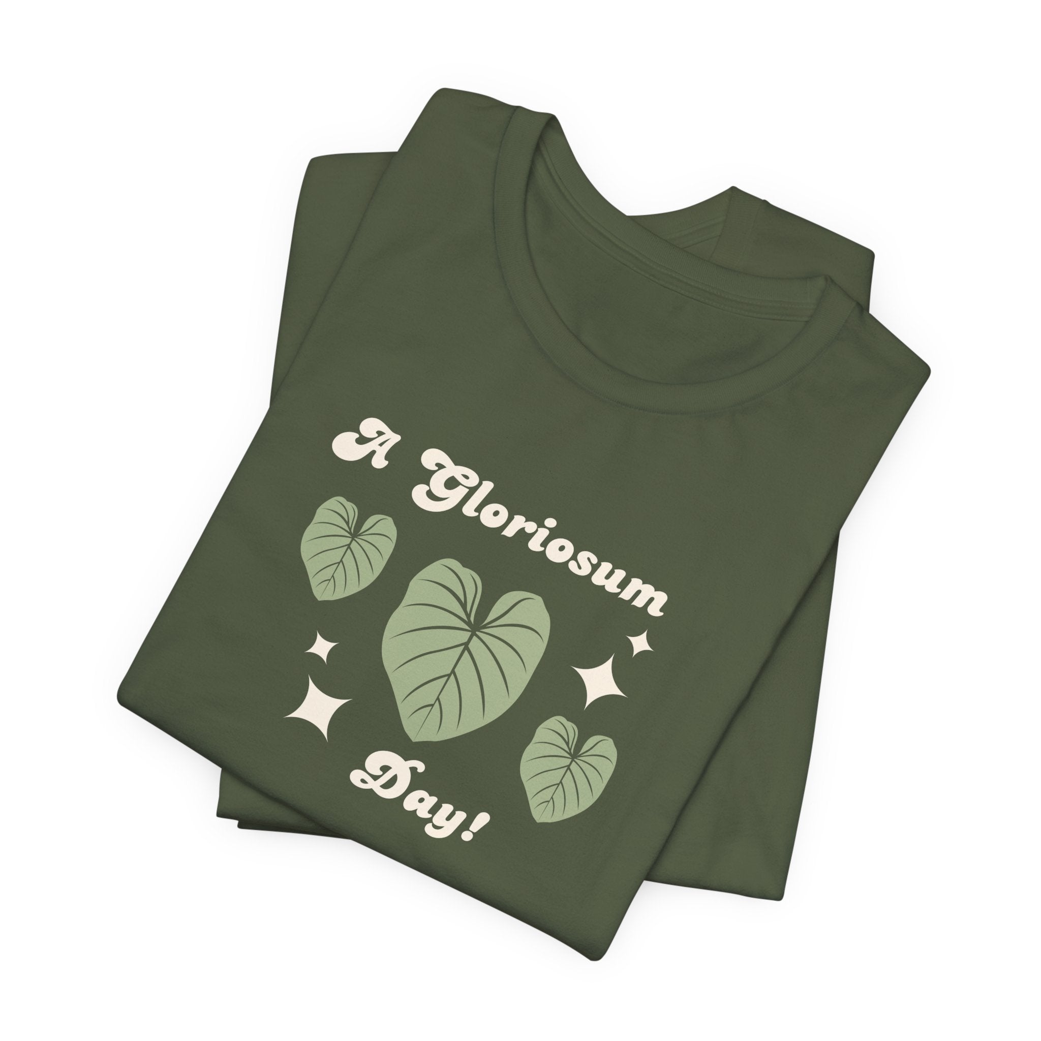 A folded military green t-shirt with text that says "A gloriosum day!"  The shirt design also has leaves from the philodendron gloriosum plant.
