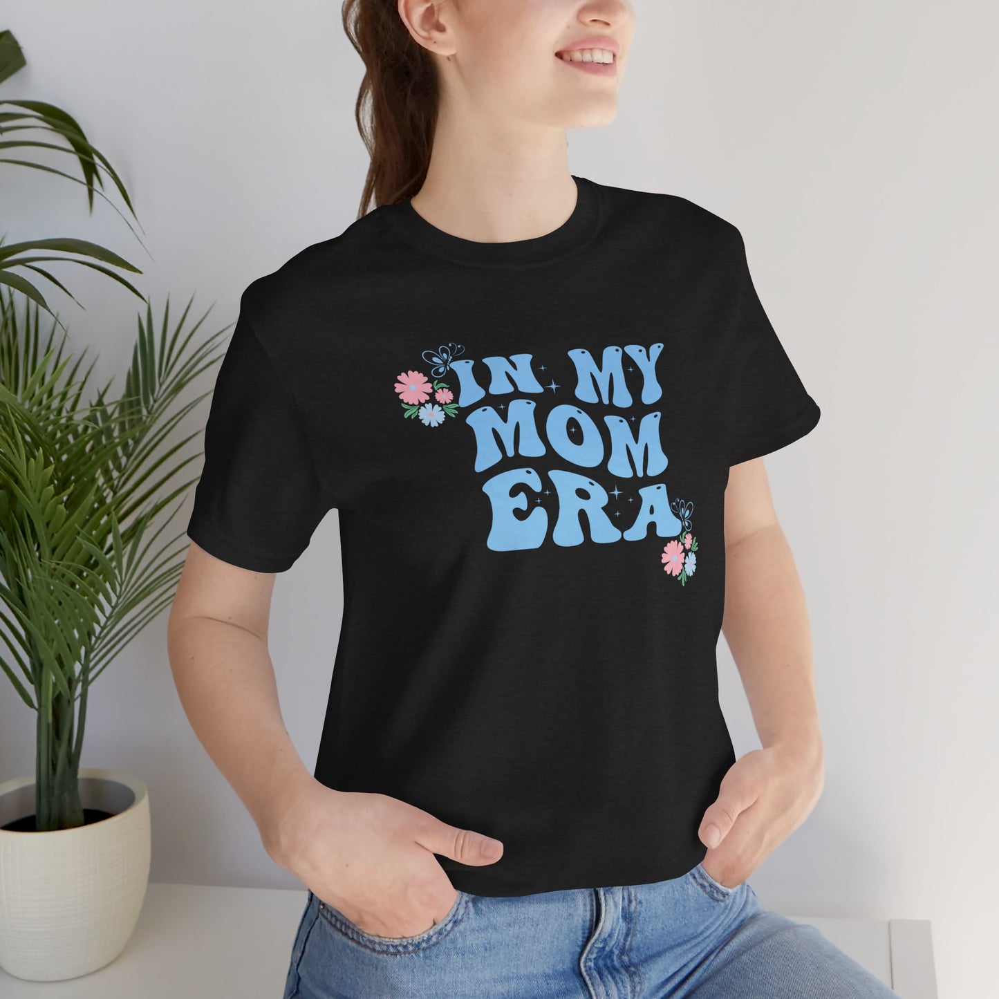 A person wearing a graphic tee with the words "In my mom era" printed in blue.