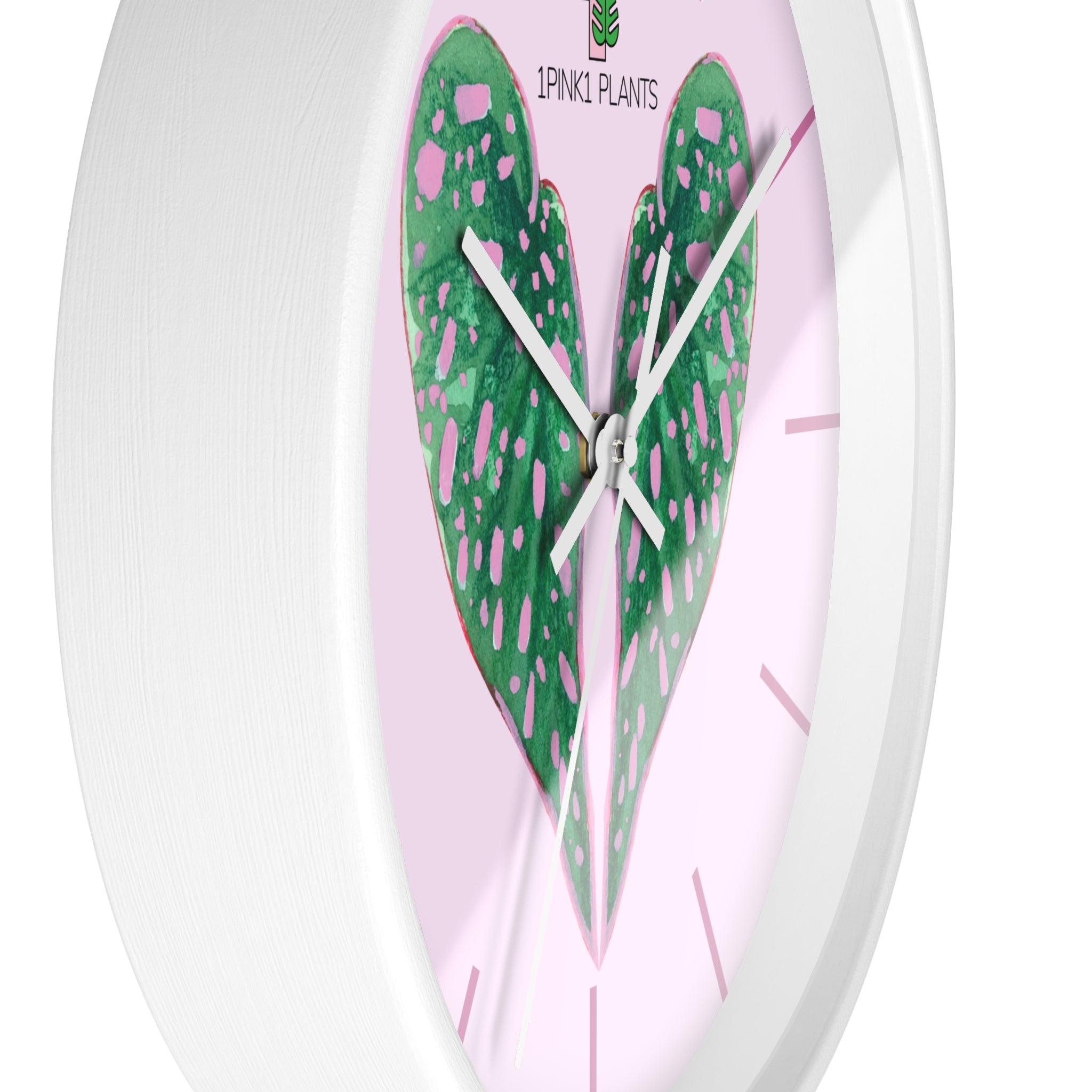 Wall clock with green leaf design on a pink background