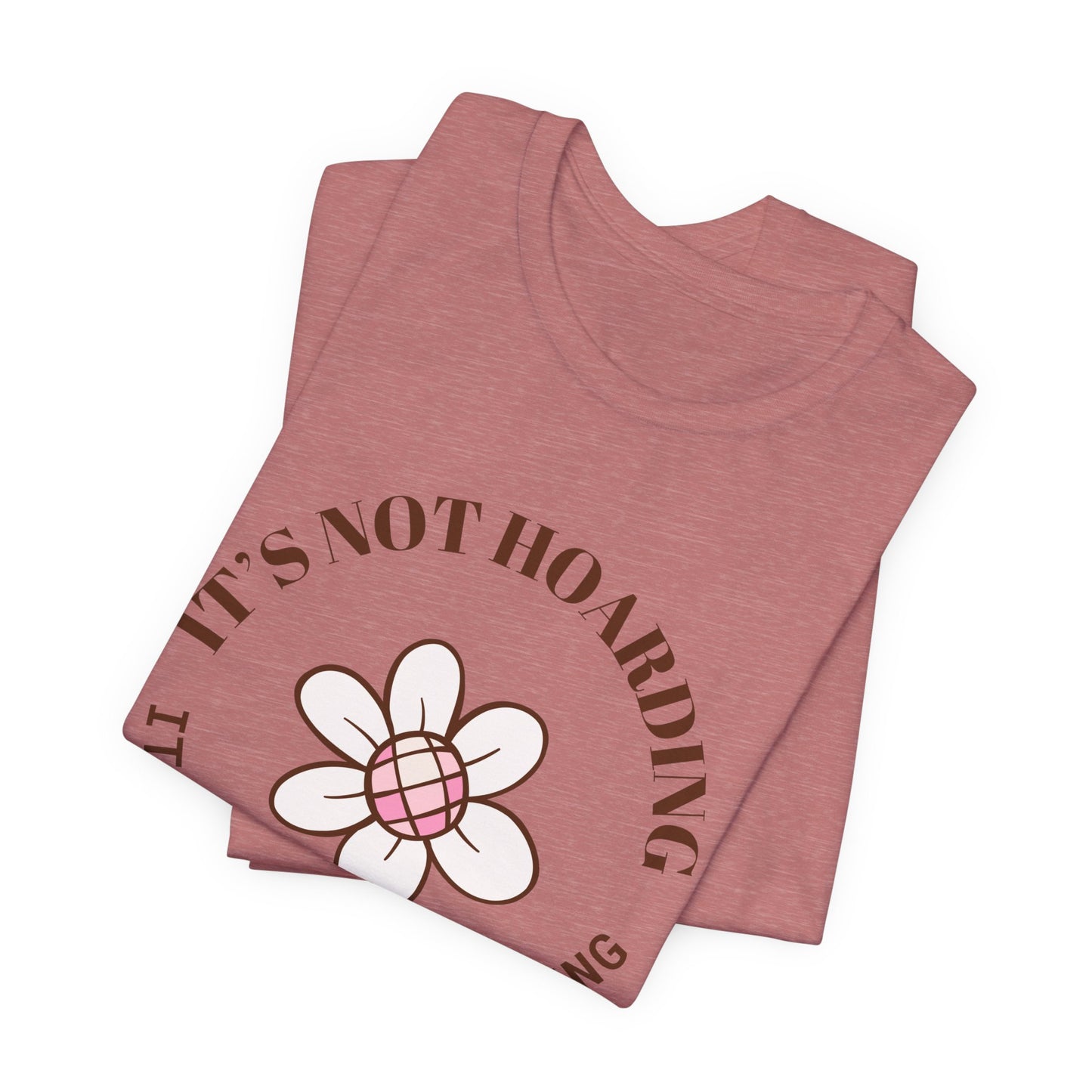 A folded heather mauve colored shirt with text that says "It's not hoarding" "It's plant collecting." The shirt design also has a groovy flower. The shirt is an excellent gift for teen and adult female houseplant collectors.