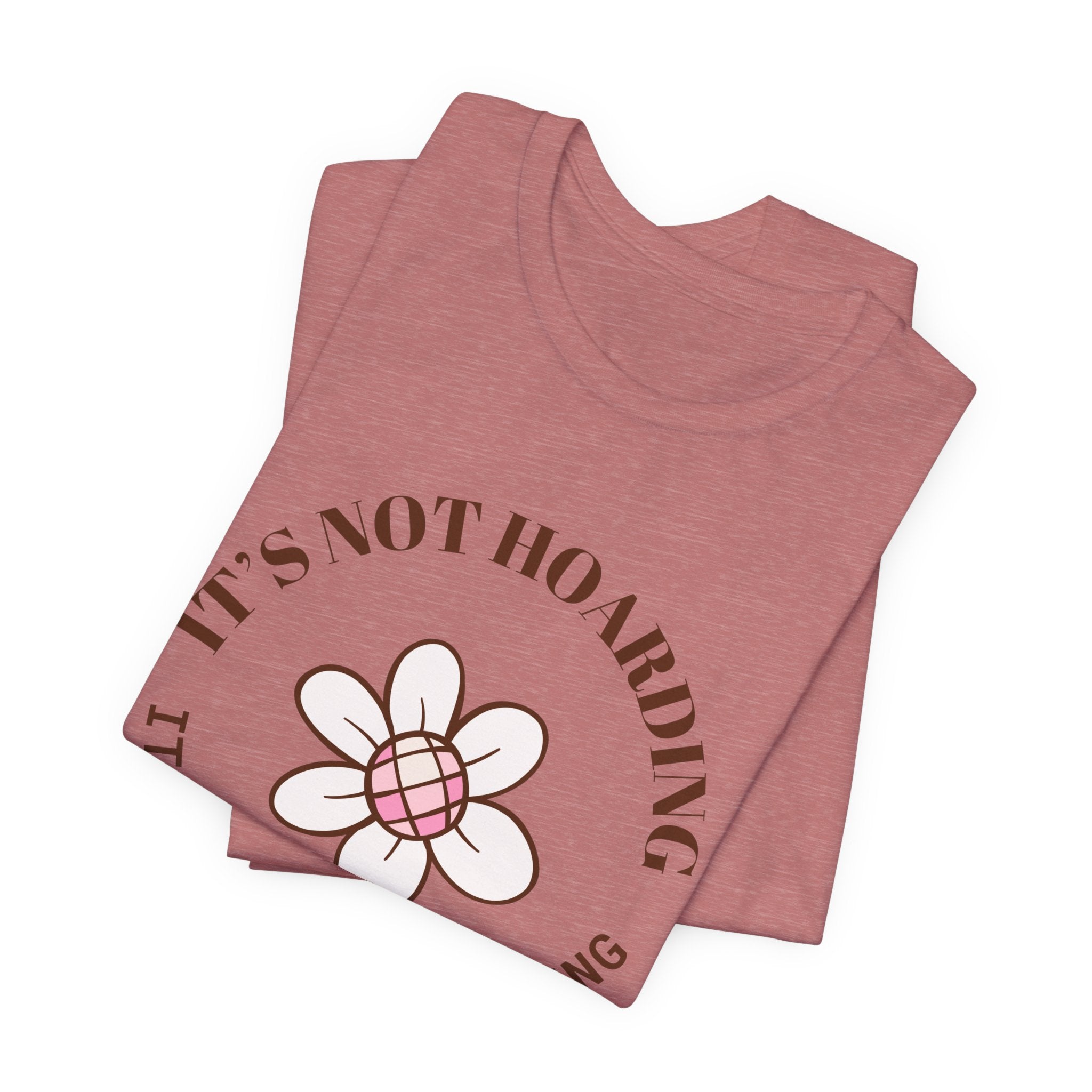 A folded heather mauve colored shirt with text that says "It's not hoarding" "It's plant collecting."  The shirt design also has a groovy flower. The shirt is an excellent gift for teen and adult female houseplant collectors.
