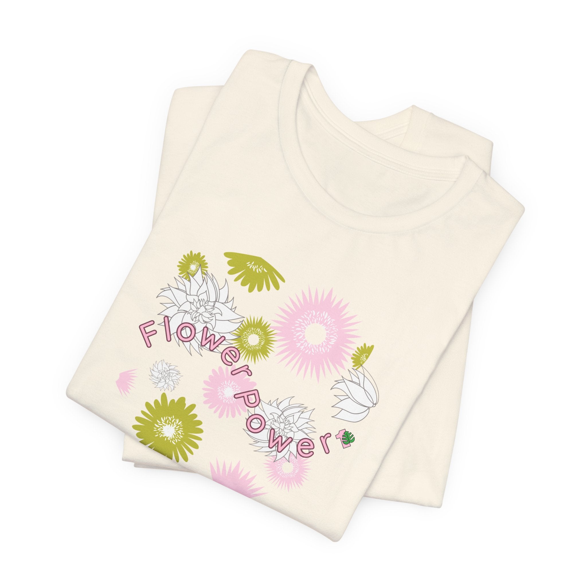 A folded natural color tee shirt with the words flower power in pink.  There are also pink, white, and green flowers printed on the shirt.
