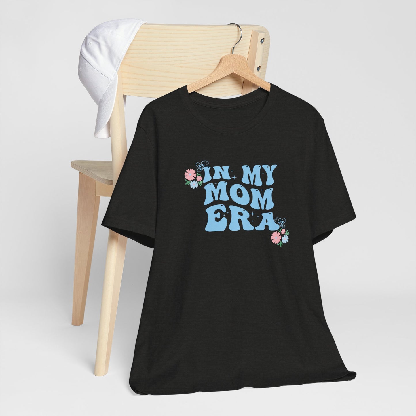 a black heather colored tee shirt with the words "In my mom era" printed in blue.