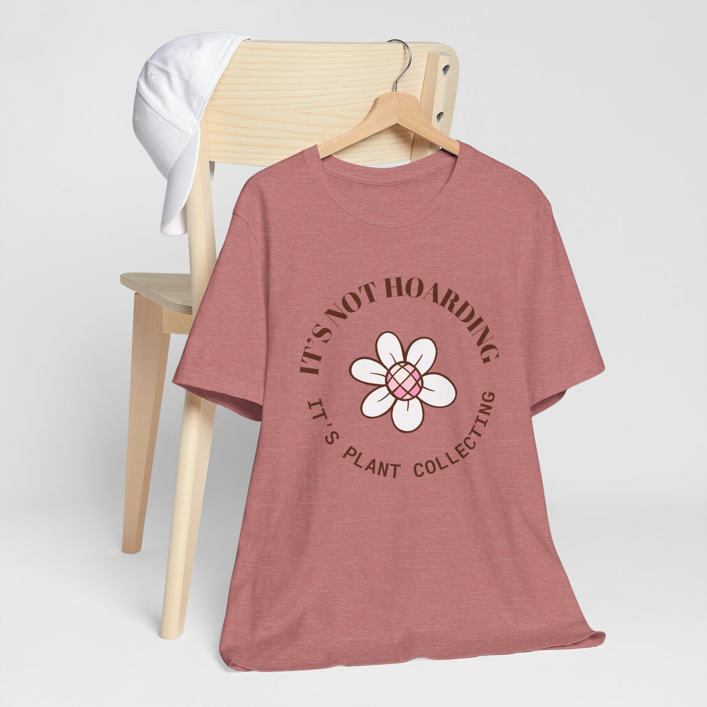 A heather mauve colored shirt with text that says "It's not hoarding" "It's plant collecting." The shirt design also has a groovy flower. The shirt is an excellent gift for teen and adult female houseplant collectors. Perfect for birthdays and Christmas gifts.