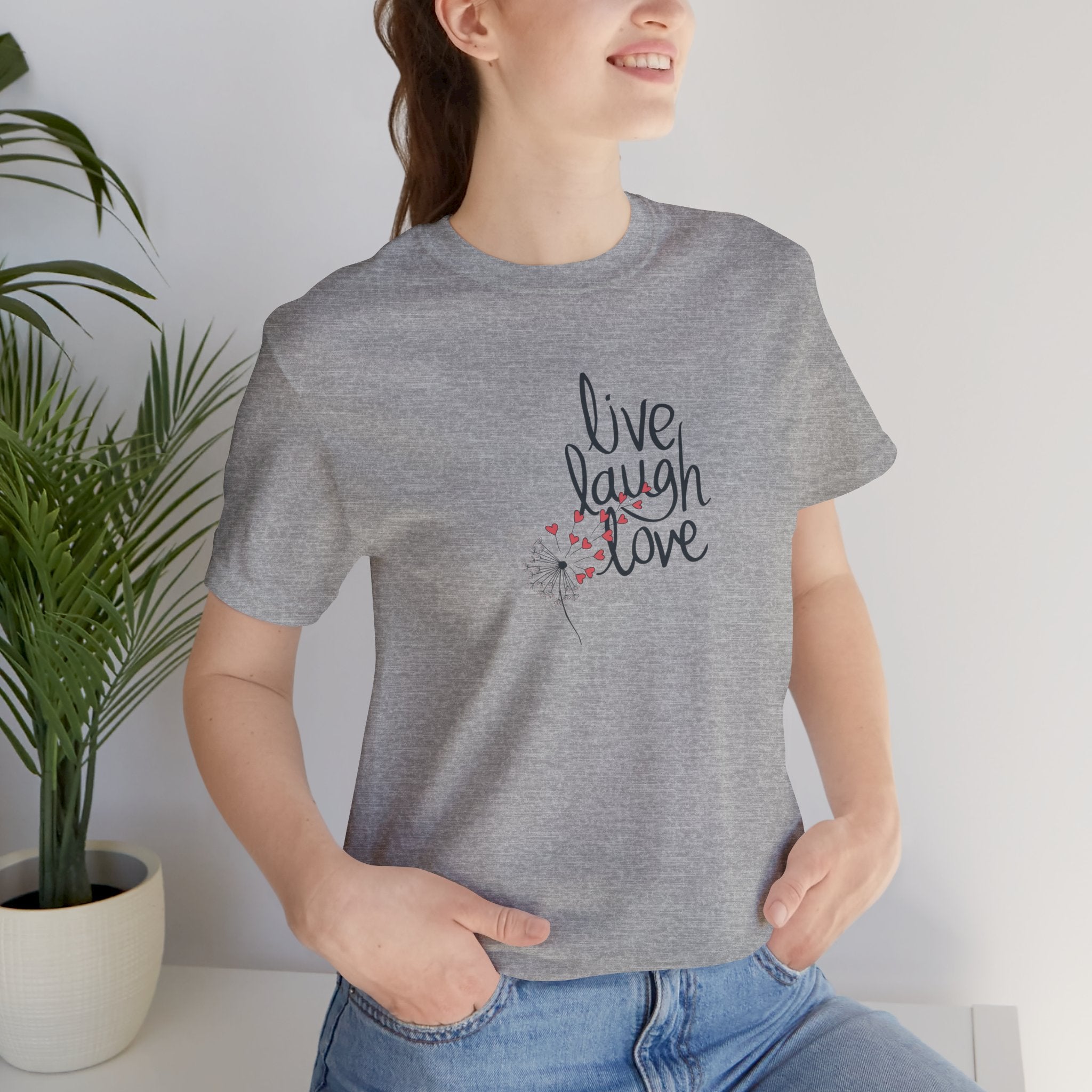 a person wearing a tee with text that says "live, laugh, love," and a dandelion with hearts.