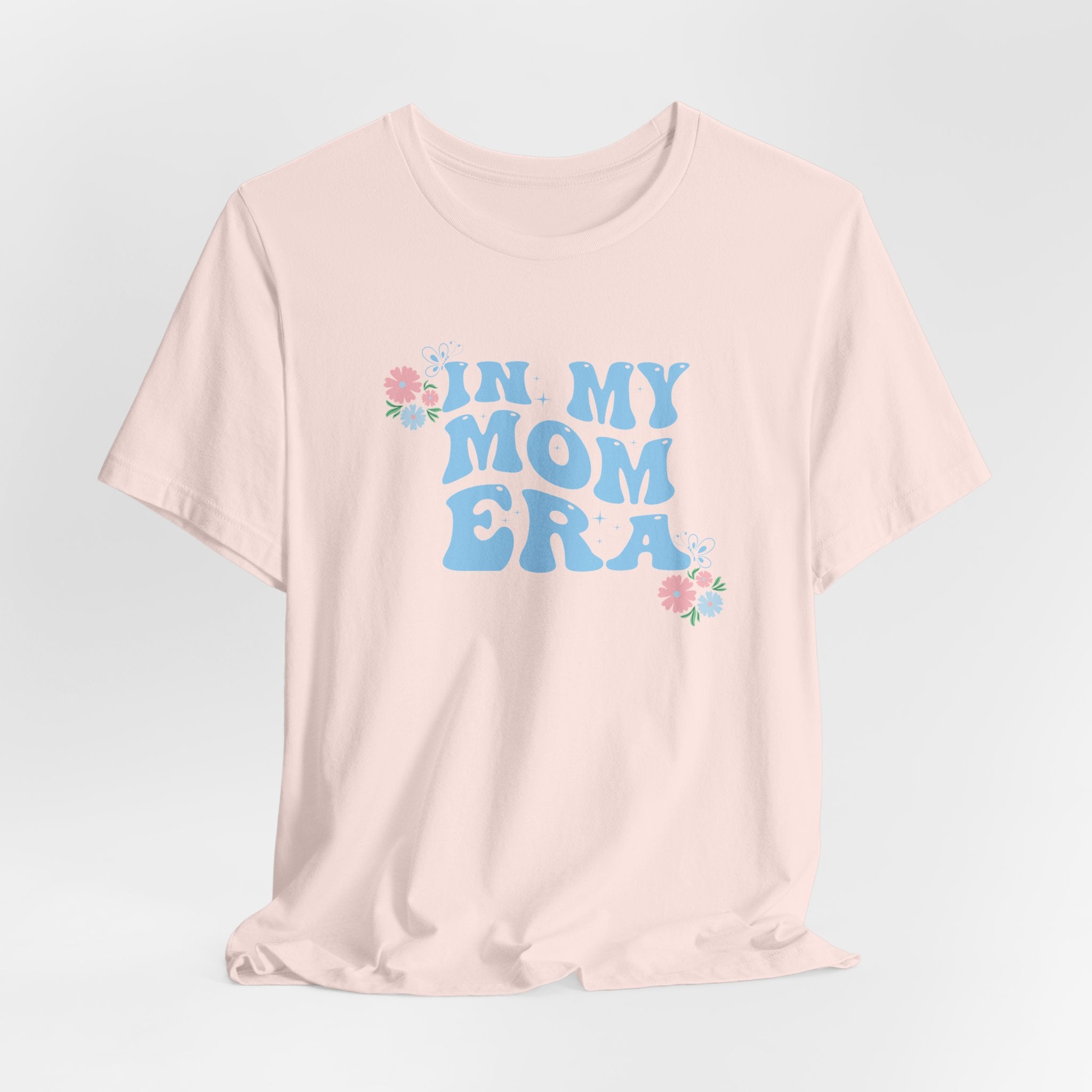 a pink tee shirt with the words "In my mom era" printed in blue. This shirt makes an excellent t-shirt for a women that is expecting.