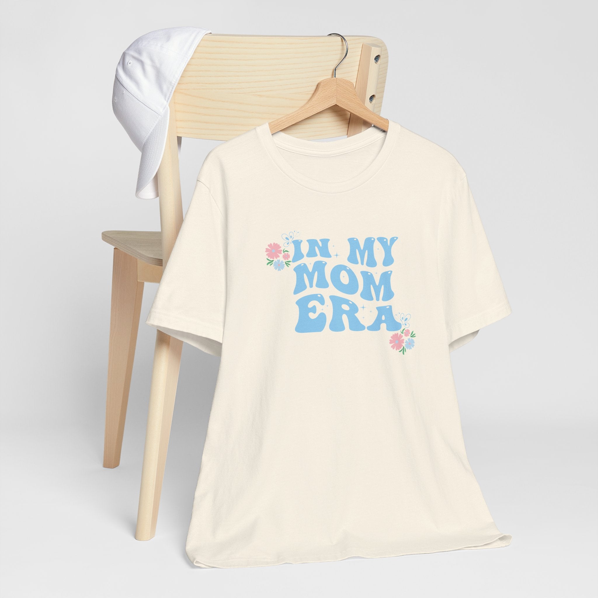 a natural color graphic tee with the words "In my mom era" printed in blue. 