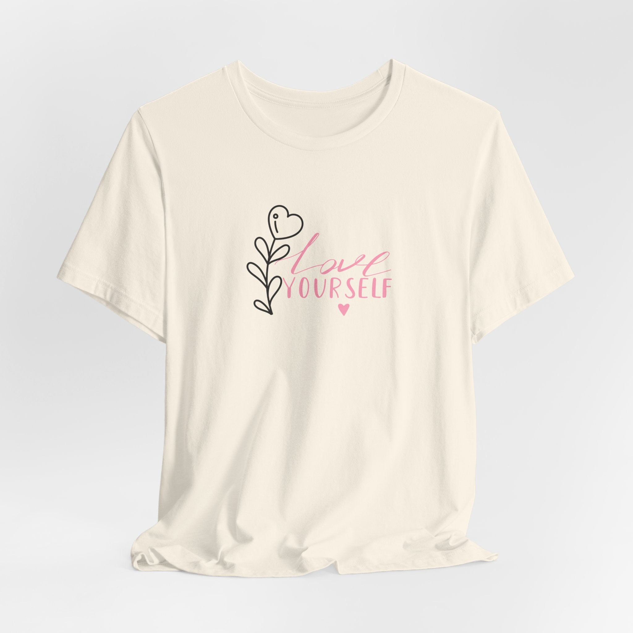 Picture of a natural color tee shirt with pink text that says "love yourself".  