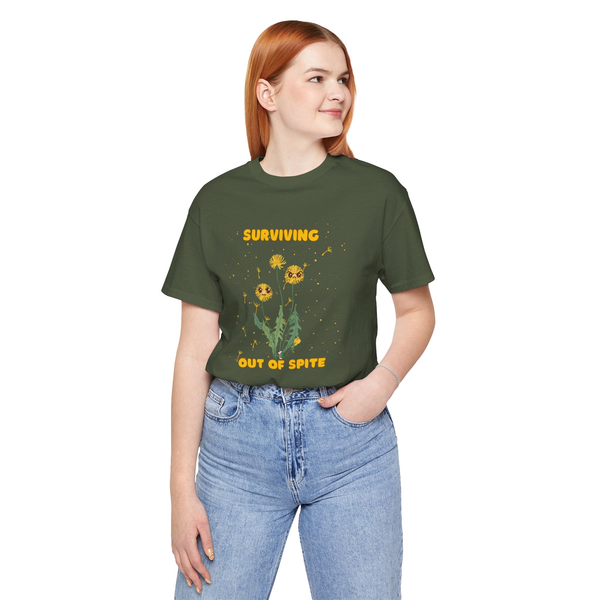 A person wearing a military green color t-shirt with yellow "surviving out of spite" funny text and dandelion plants with a funny look printed on the front of the shirt.  Perfect t-shirt for plant lovers. 