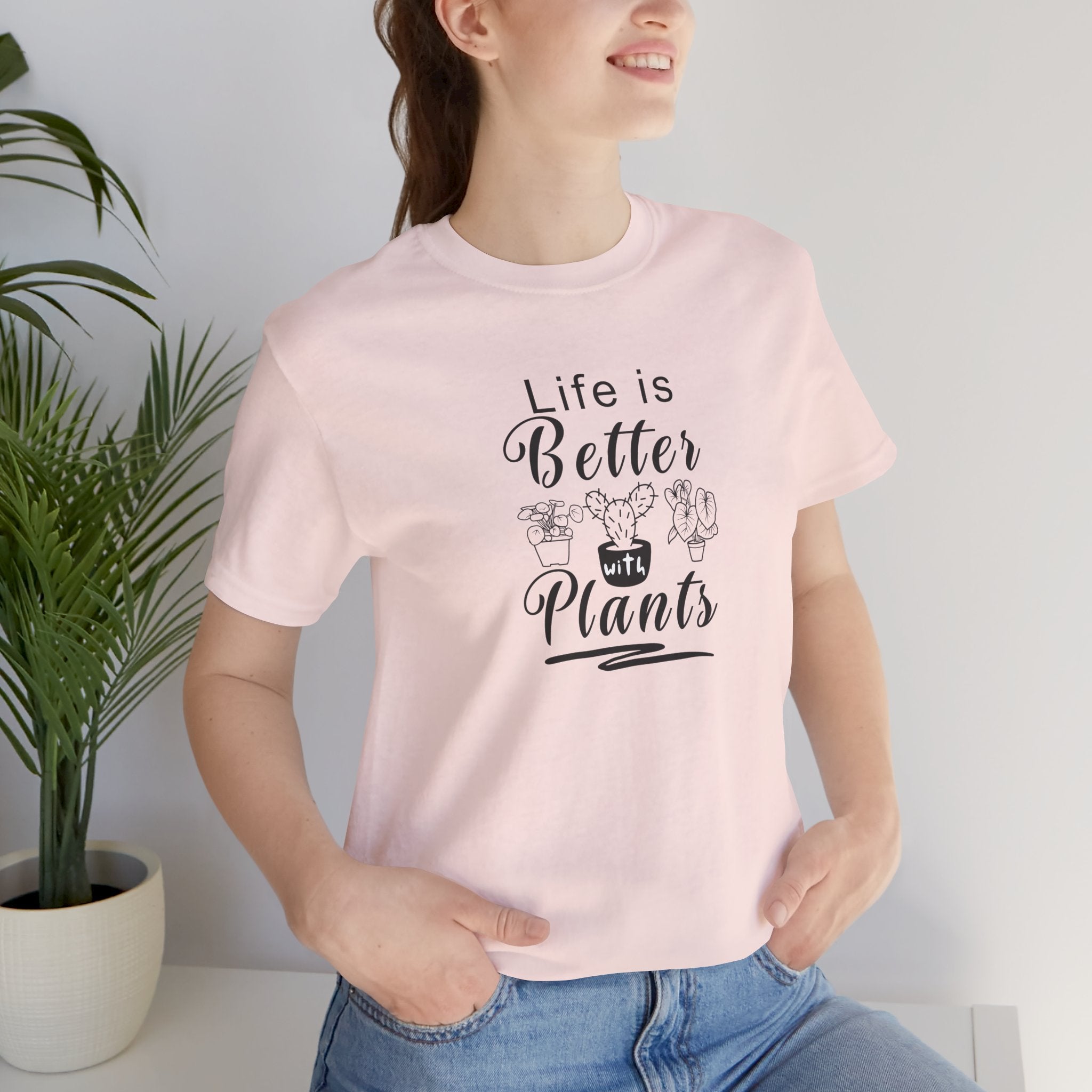 a person wearing a pink shirt with "Life is Better with Plants" text in black  
