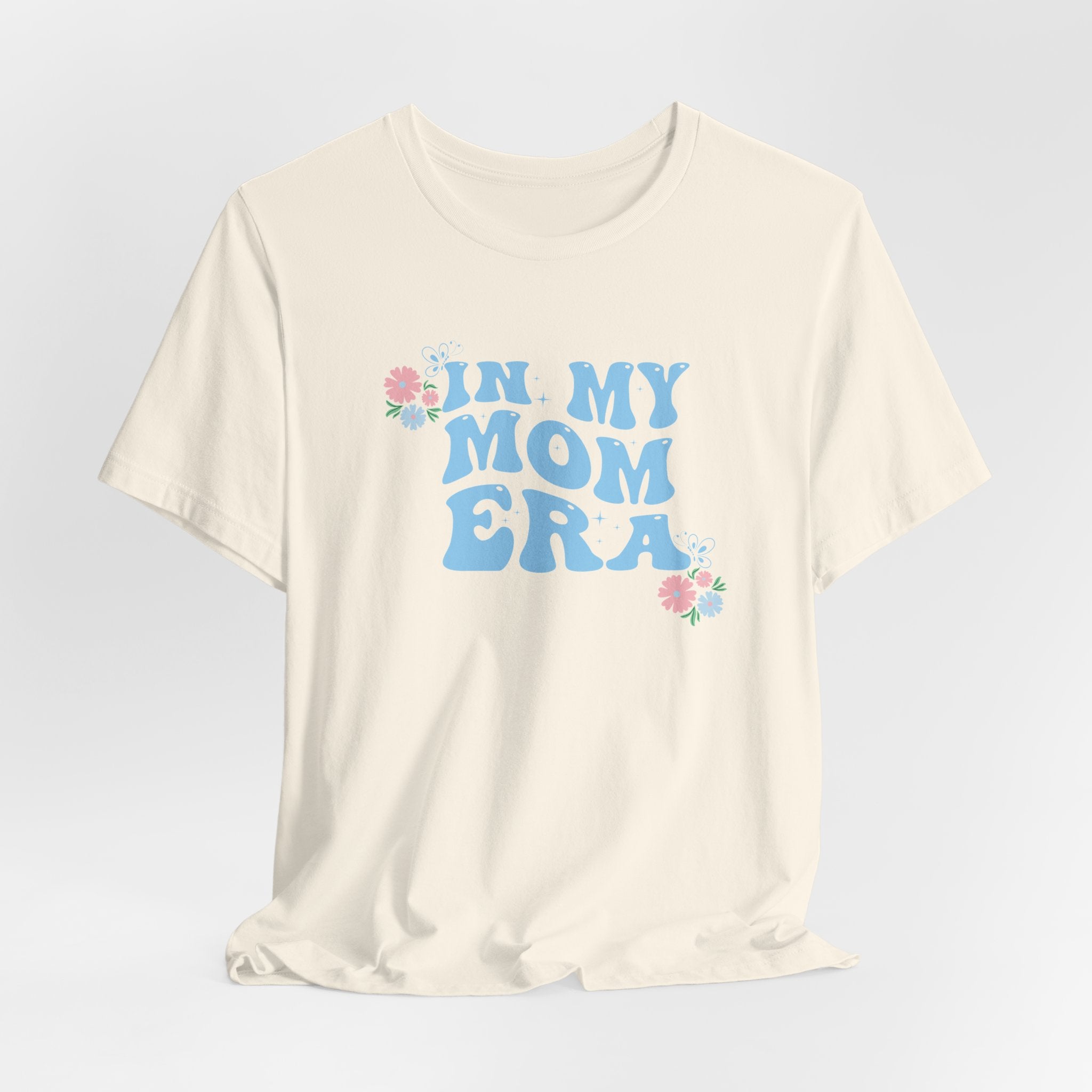 a natural color graphic tee with the words "In my mom era" printed in blue. 