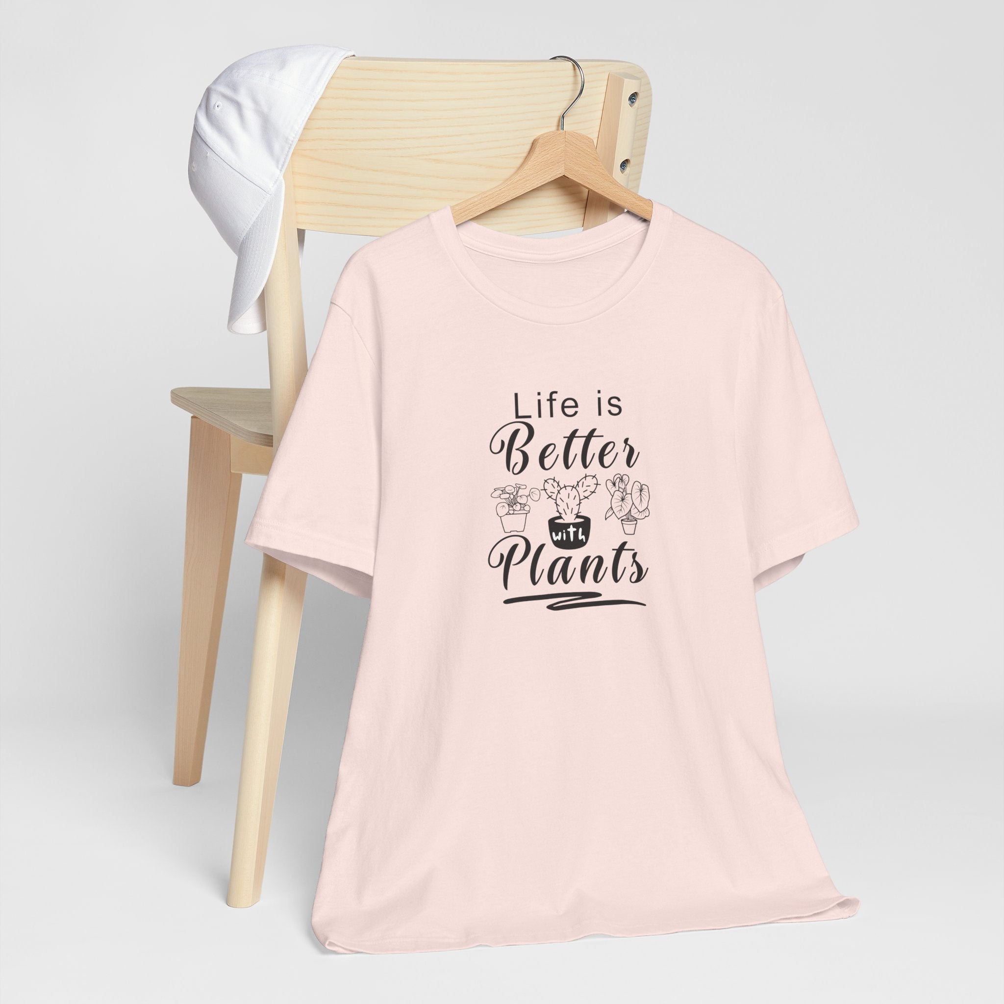 a hanging pink shirt with "Life is Better with Plants" text in black  