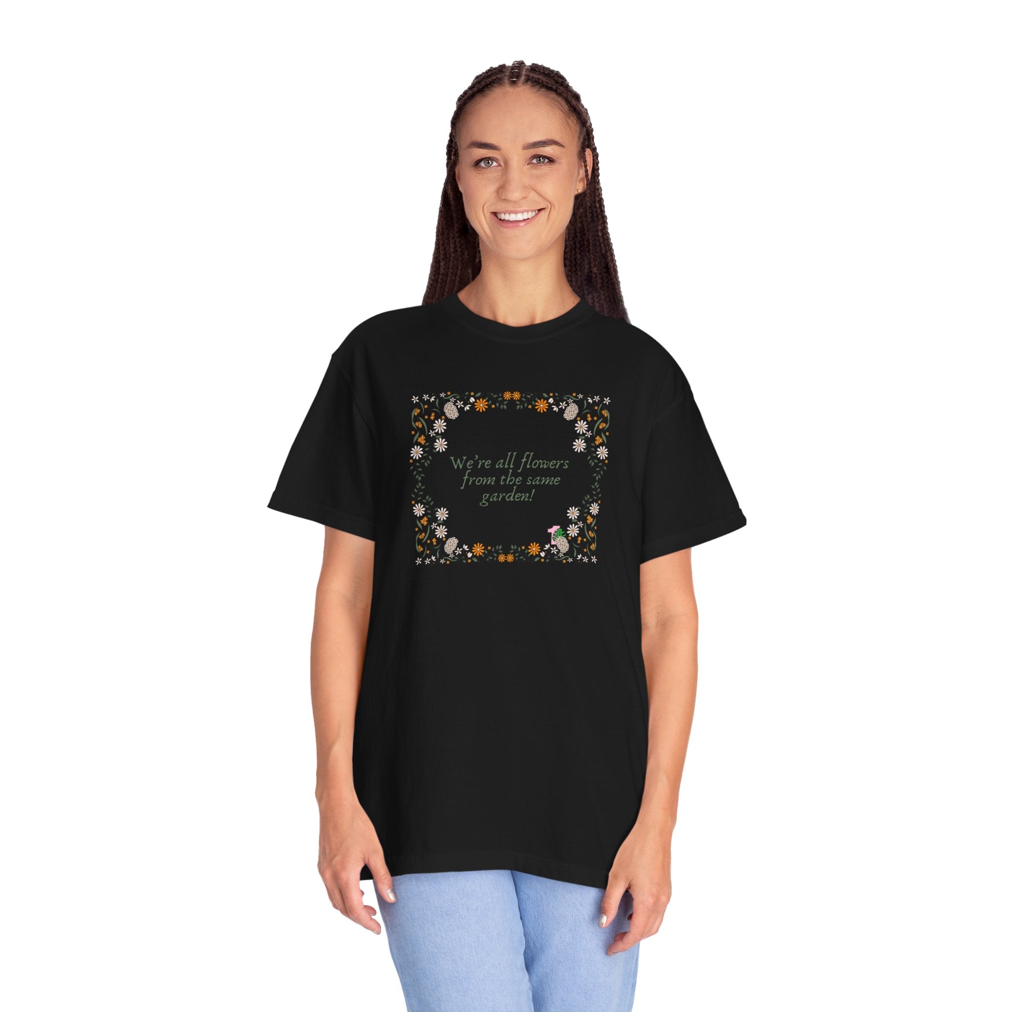 A person wearing a black tee shirt with a sentence that says "we're all flowers from the same garden!" 