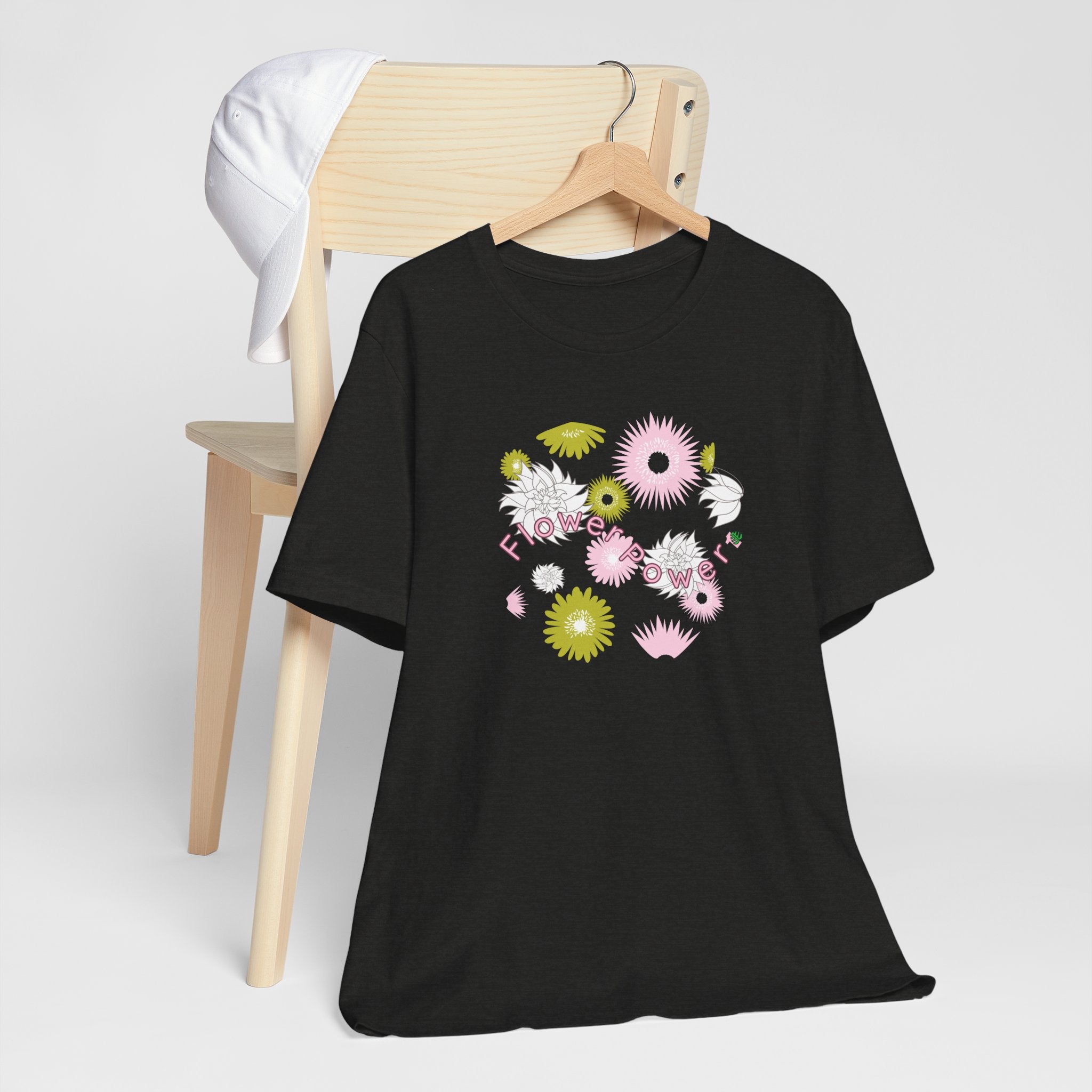 A hanging black color tee shirt with the words flower power in pink.  There are also pink, white, and green flowers printed on the shirt.