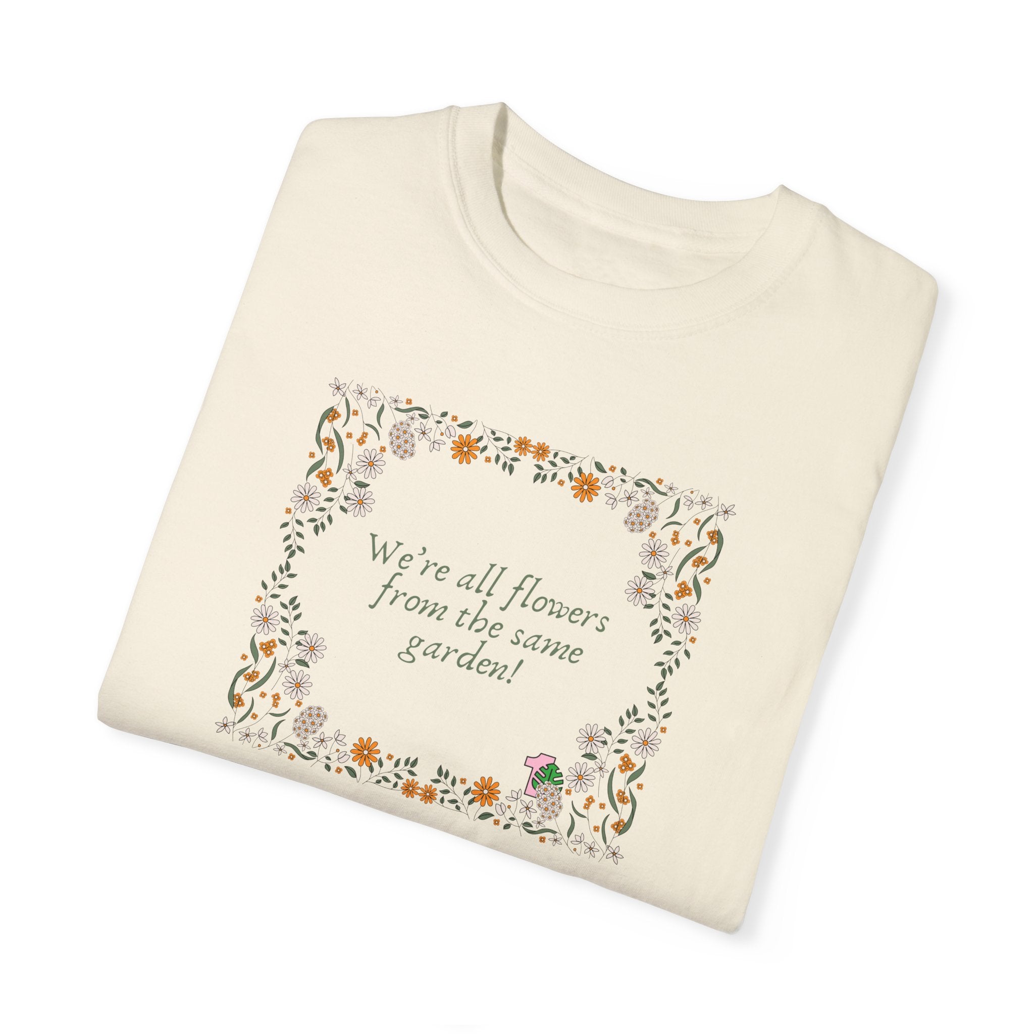 A folded tshirt with a sentence that says "we're all flowers from the same garden!" This shirt inspires kindness towards others.