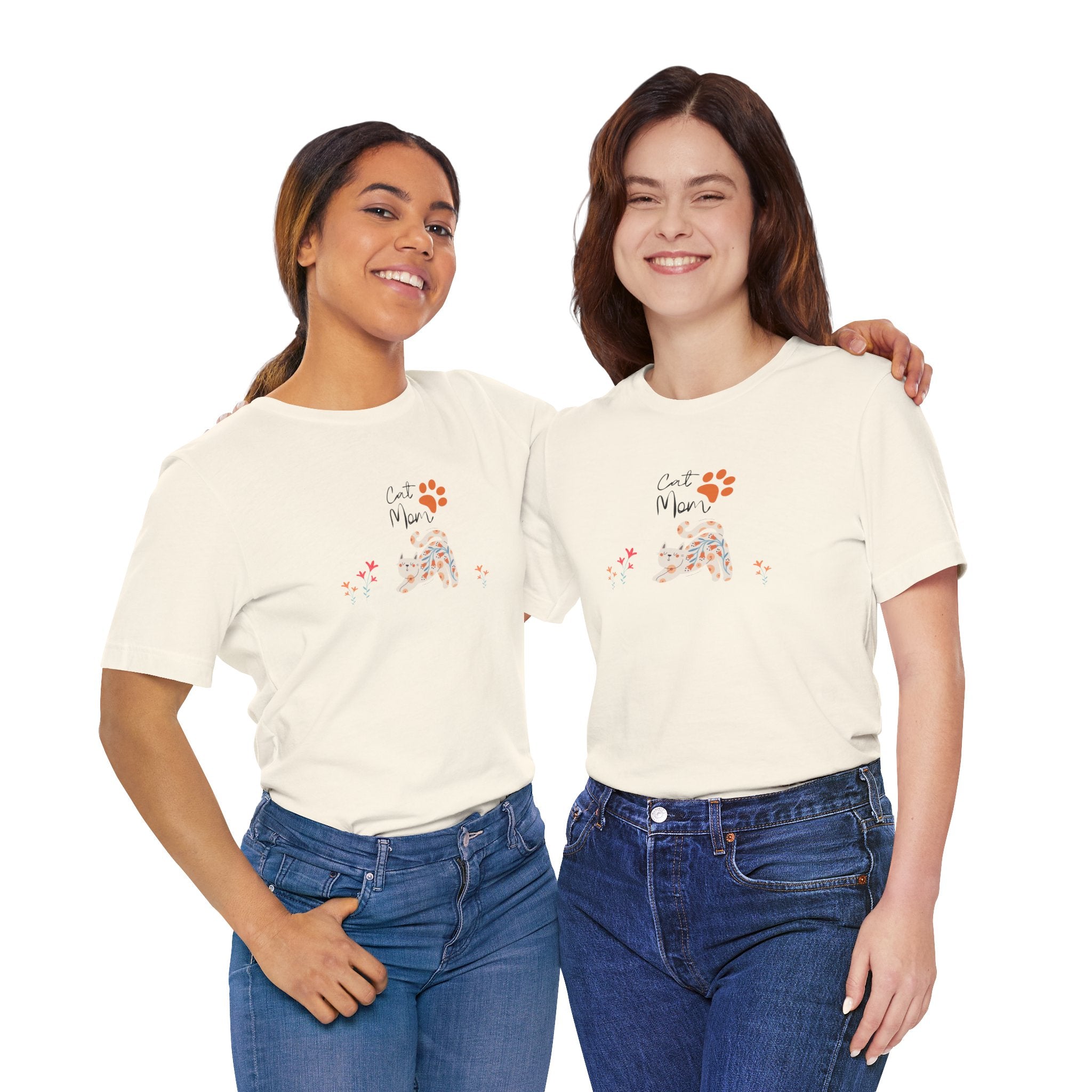 Tow ladies wearing a natural color t-shirt with the words "cat mom," a floral cat, and some flowers printed on the front of the shirt.