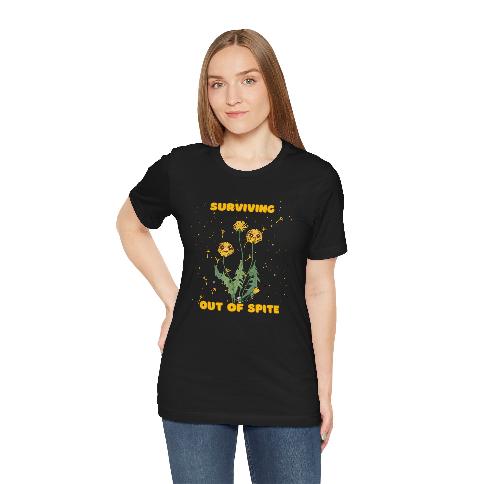 A person wearing a black plant t-shirt with yellow "surviving out of spite" funny text and dandelion plants with a funny look printed on the front of the shirt. 