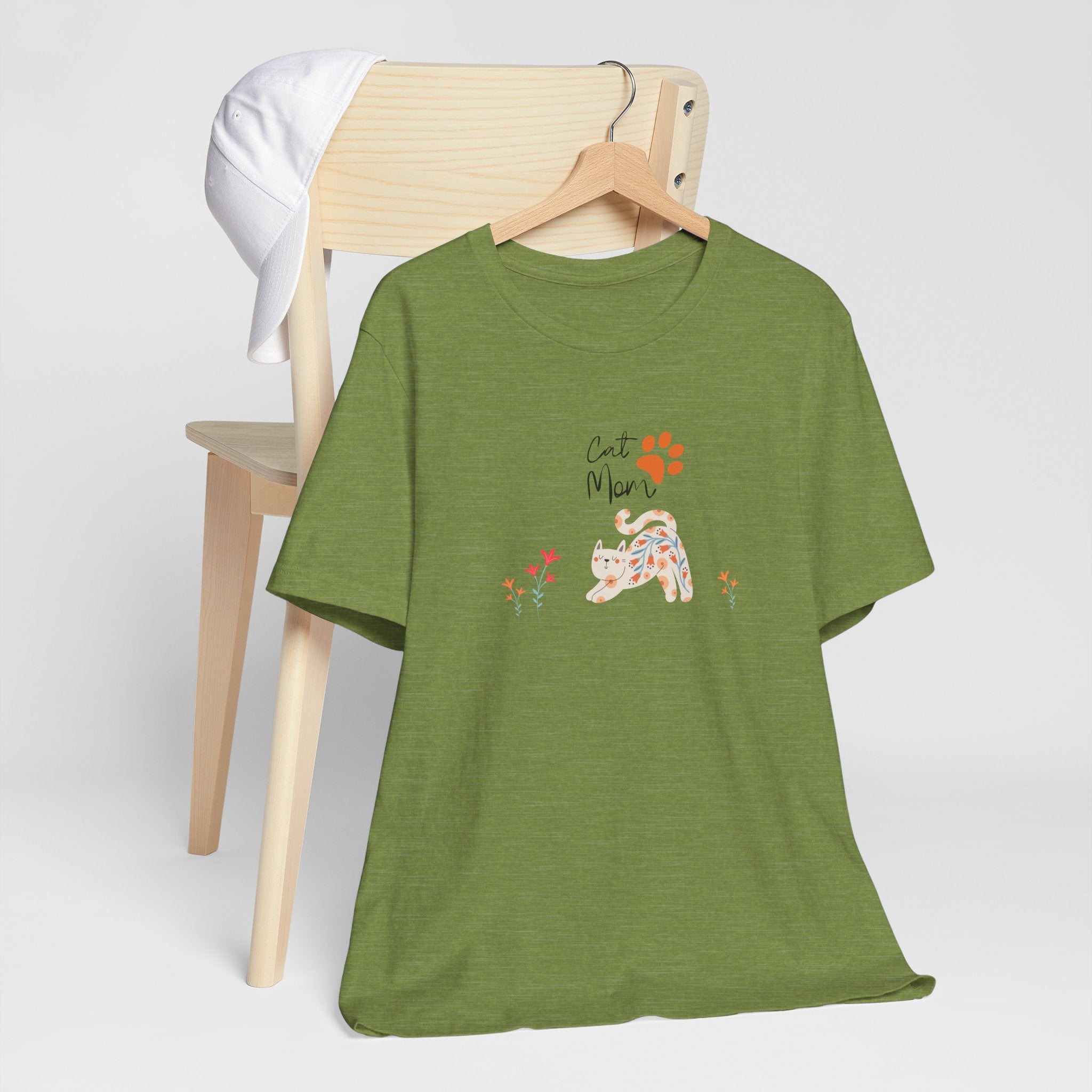 A heather green t-shirt with the words "cat mom," a floral cat, and some flowers printed on the front of the shirt.