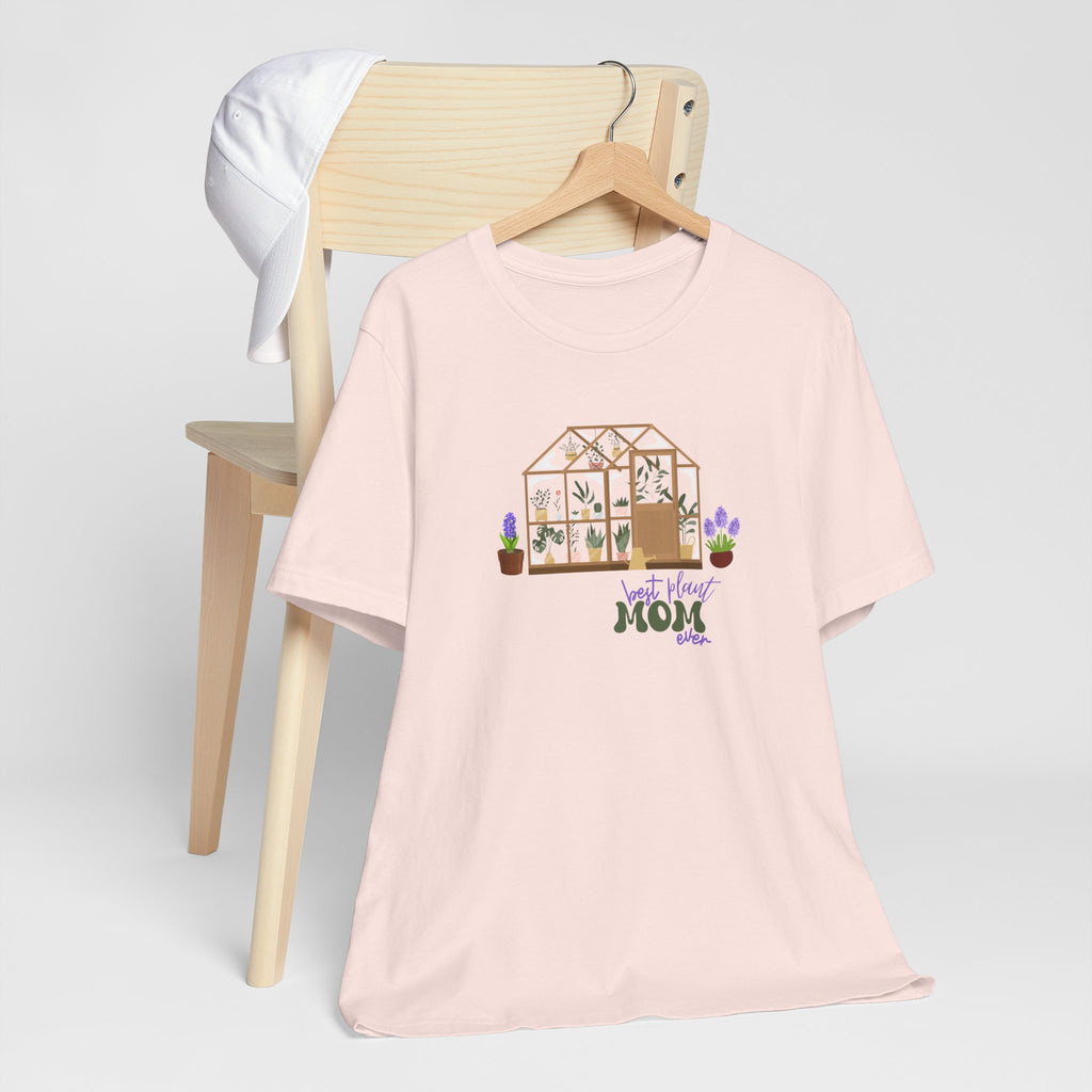 A jersey short sleeve tee in soft pink color with a printed greenhouse design.  There is also printed text that says best plant mom ever.