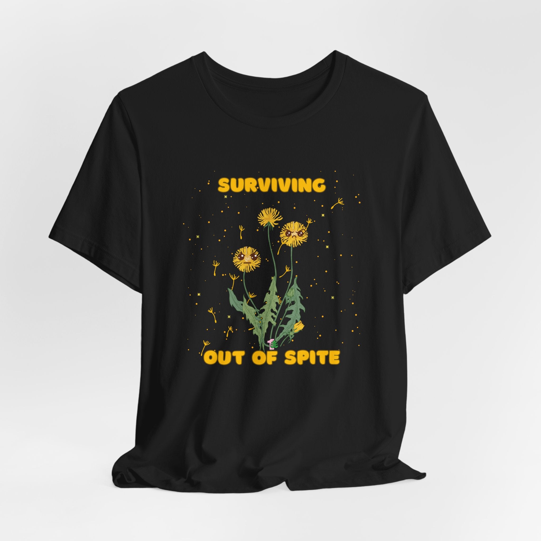 A black color t-shirt with yellow "surviving out of spite" funny text and dandelion plants with a funny look printed on the front of the shirt. 