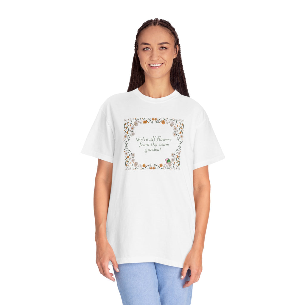 A young lady wearing a white shirt with text that says "We're all flowers from the same garden!"  The text is surrounded by a floral frame. 