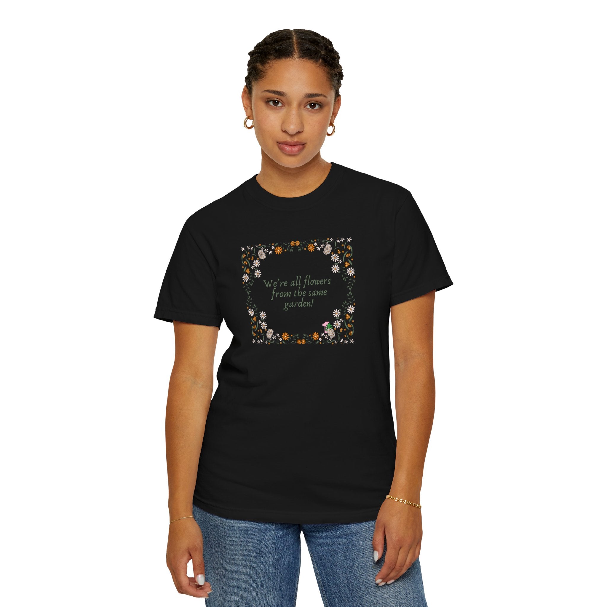 A person wearing a black shirt with a sentence that says "we're all flowers from the same garden!" 