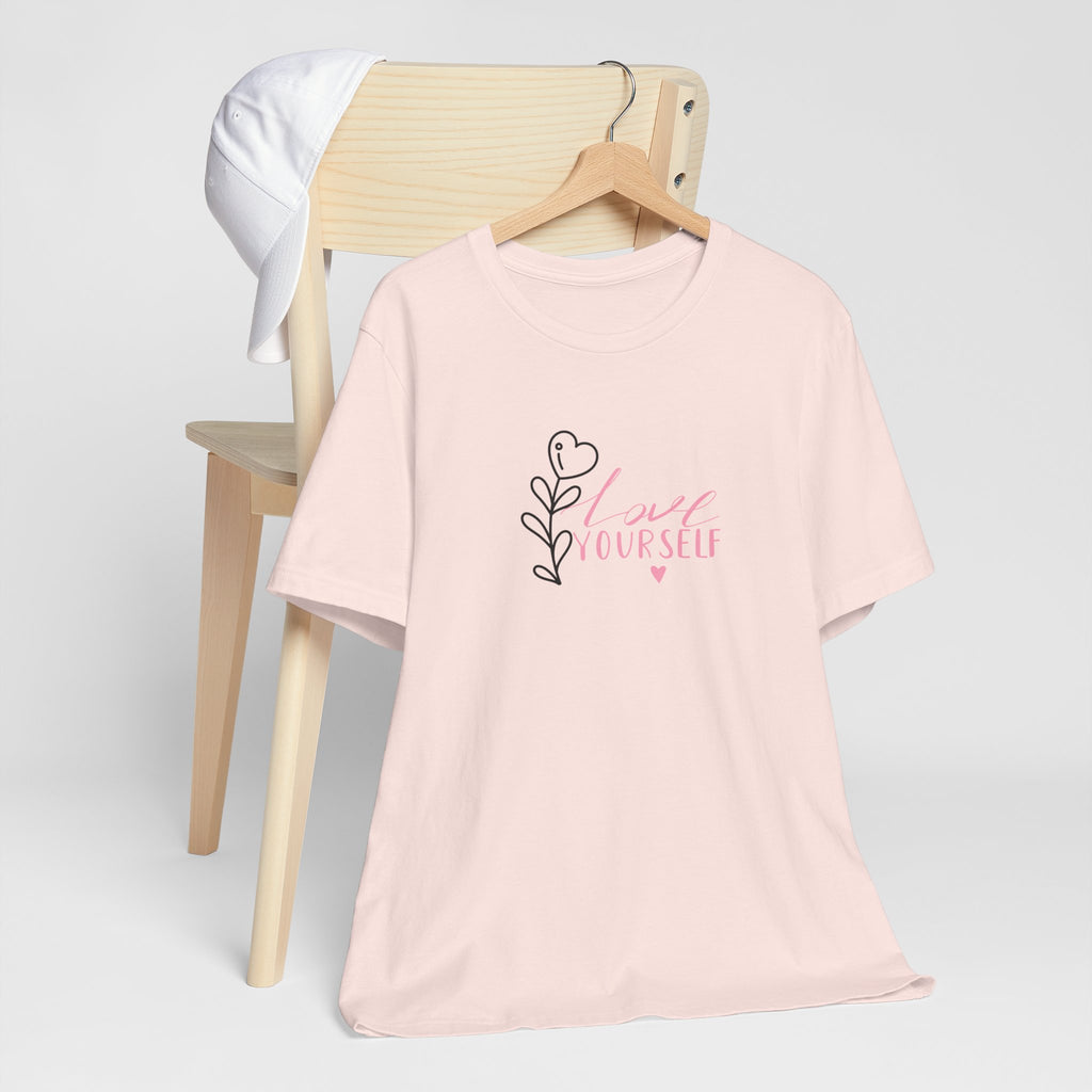 Picture of a soft pink tee shirt with the text love yourself.  This shirt encourages confidence in  the person that wears it and reads it. 
