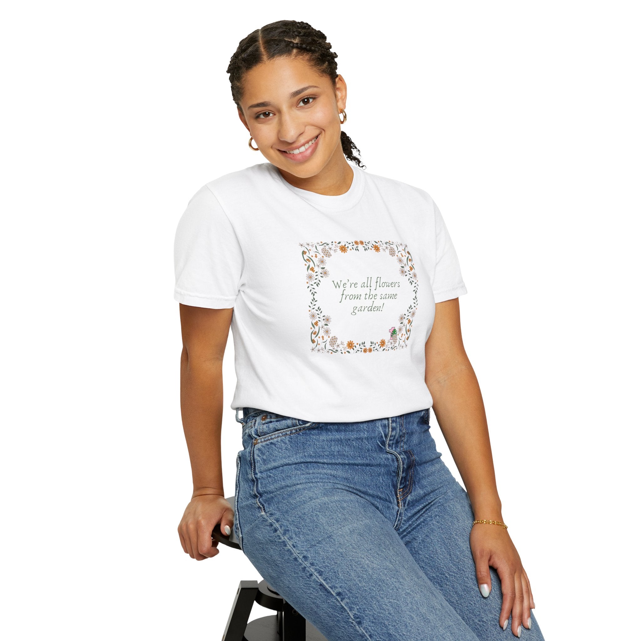 A young lady wearing a white shirt with text that says "We're all flowers from the same garden!"  The text is surrounded by a floral frame. 