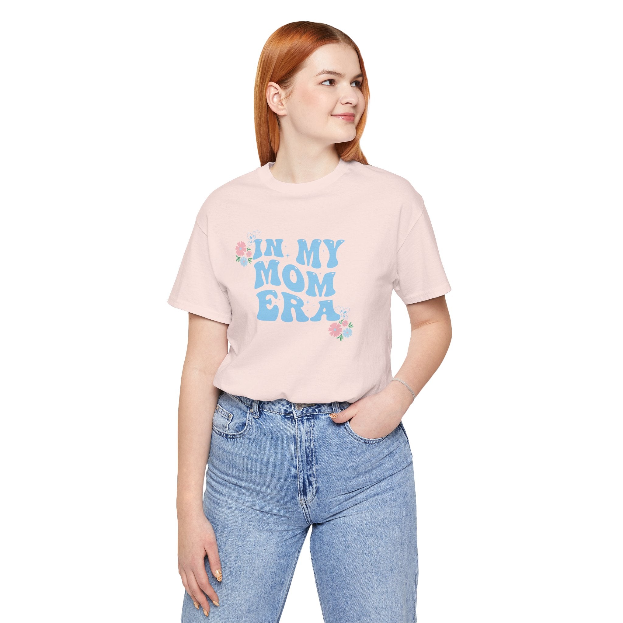 A lady wearing a pink top with the words "In my mom era" printed in blue. 