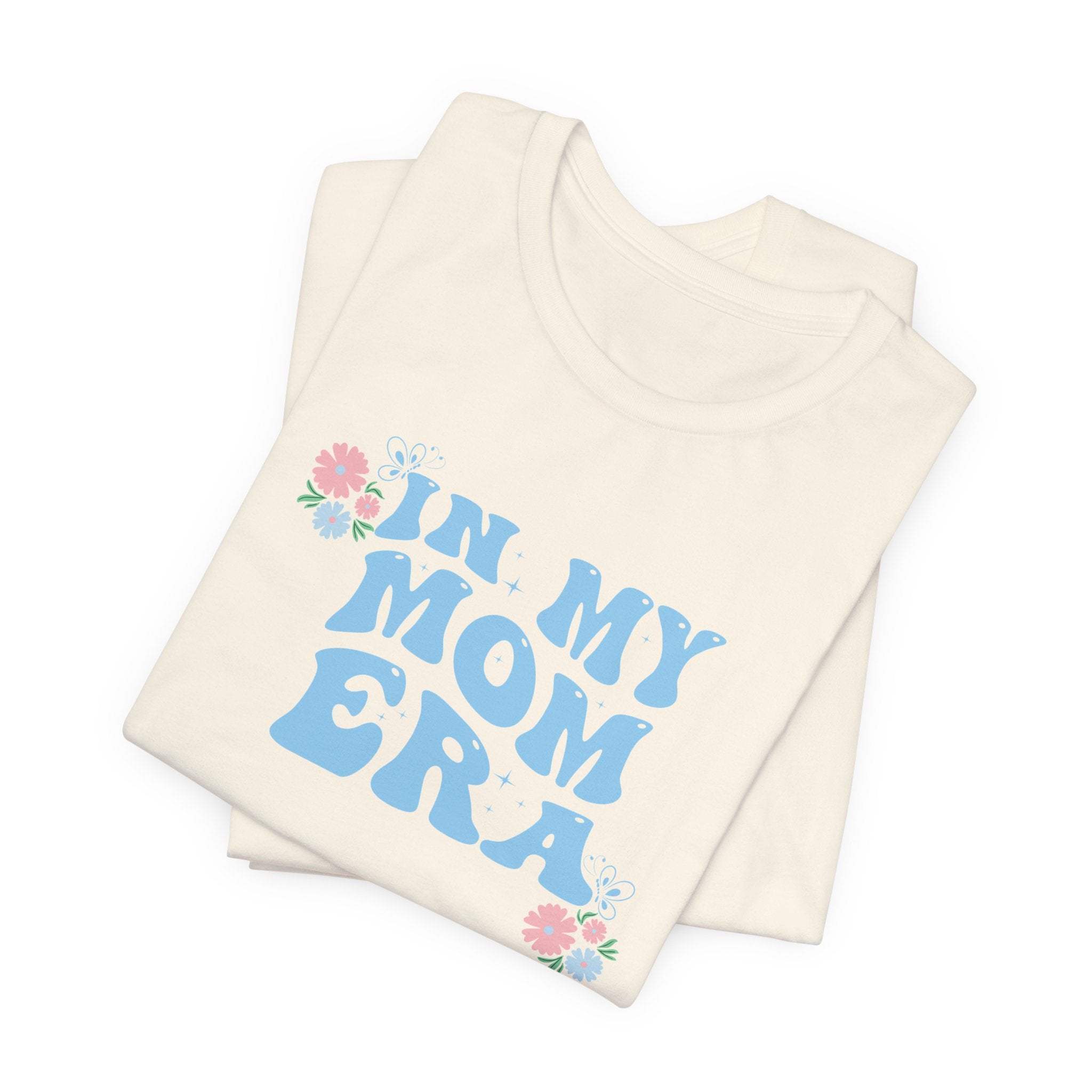 a natural color folded tee shirt with the words "In my mom era" printed in blue. This shirt makes an excellent t-shirt for soon to be moms.