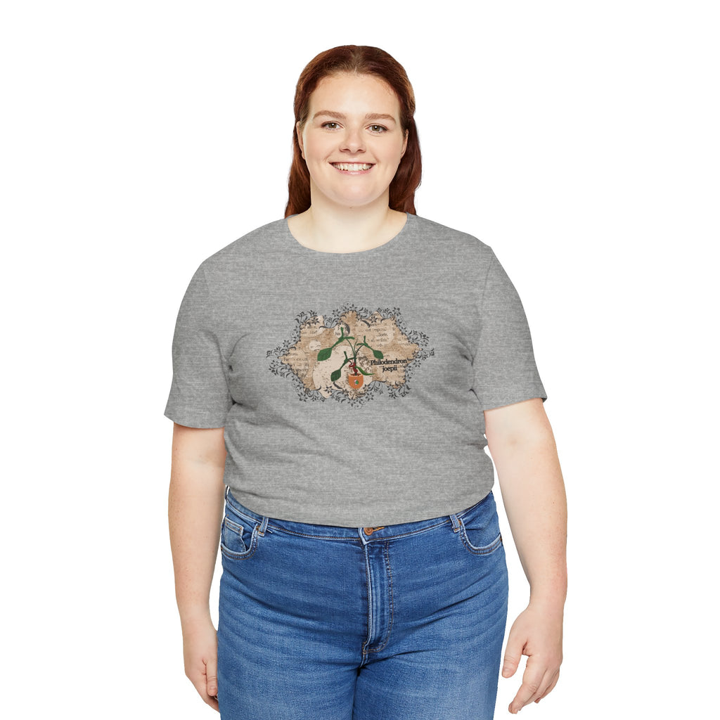 A tee shirt with a philodendron joepii plant design, an ant eating the plant, and the 1pink1 plants logo. Perfect plant shirt for a friend.