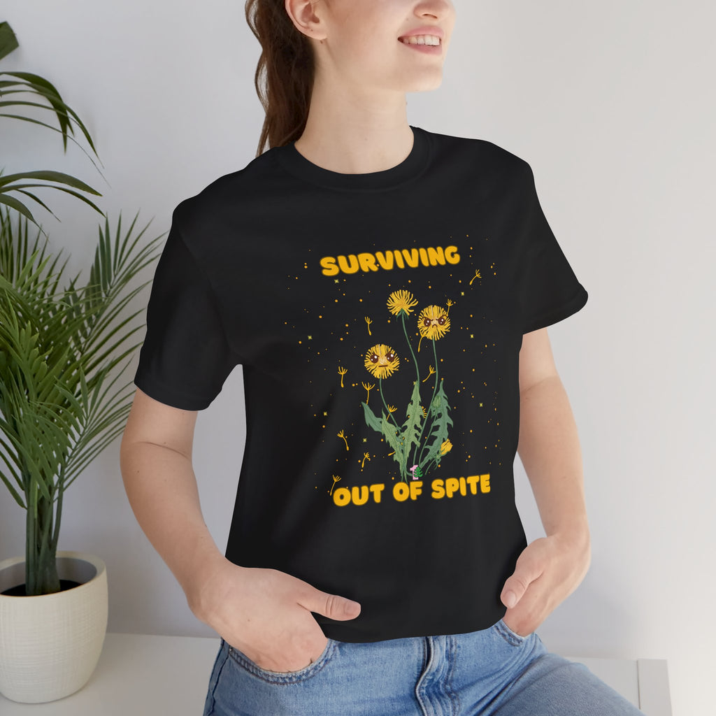 A person wearing a black plant t-shirt with yellow "surviving out of spite" funny text and dandelion plants with a funny look printed on the front of the shirt. 