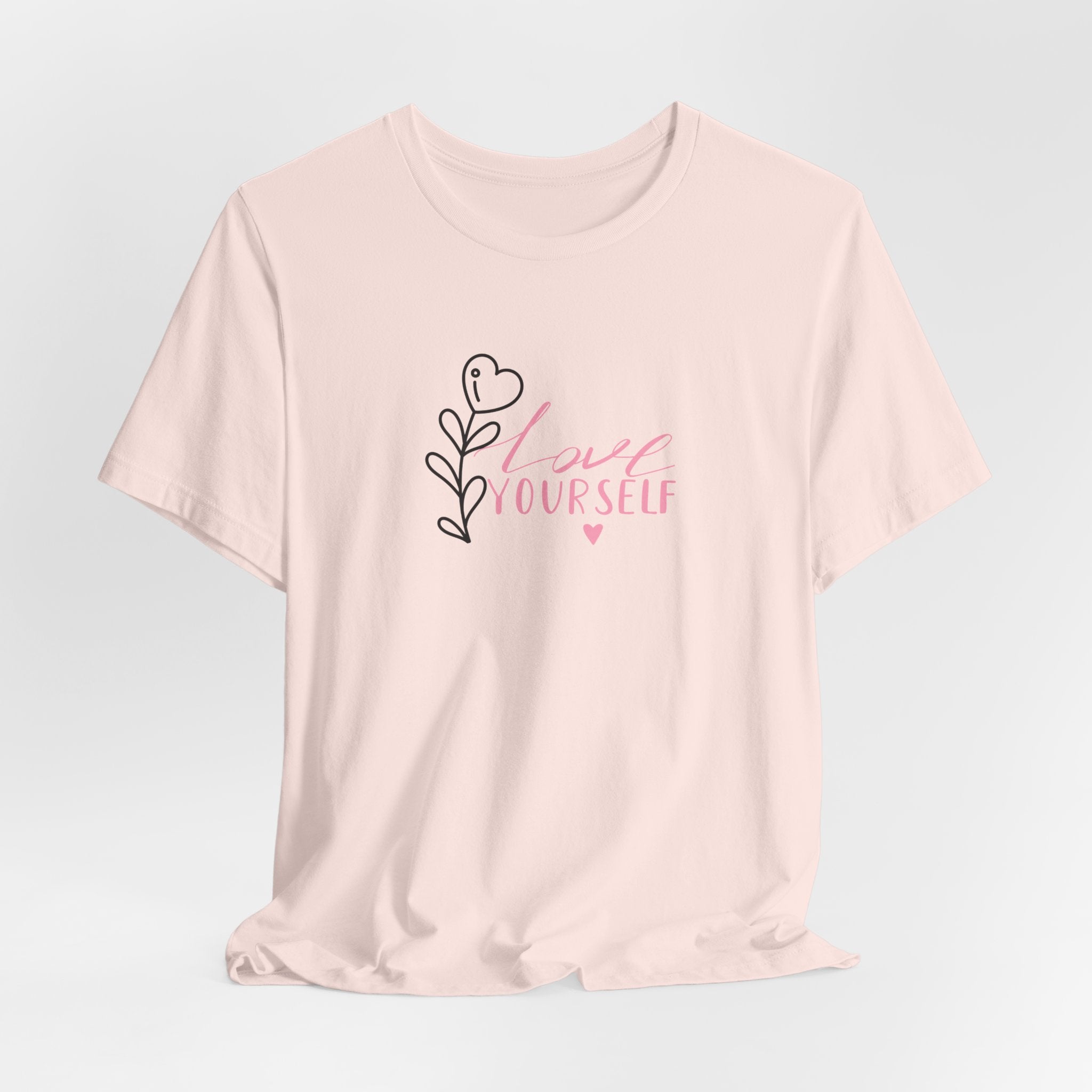 picture of a soft pink tee with the text love yourself.  This shirt encourages confidence in  the person that wears it and reads it. 