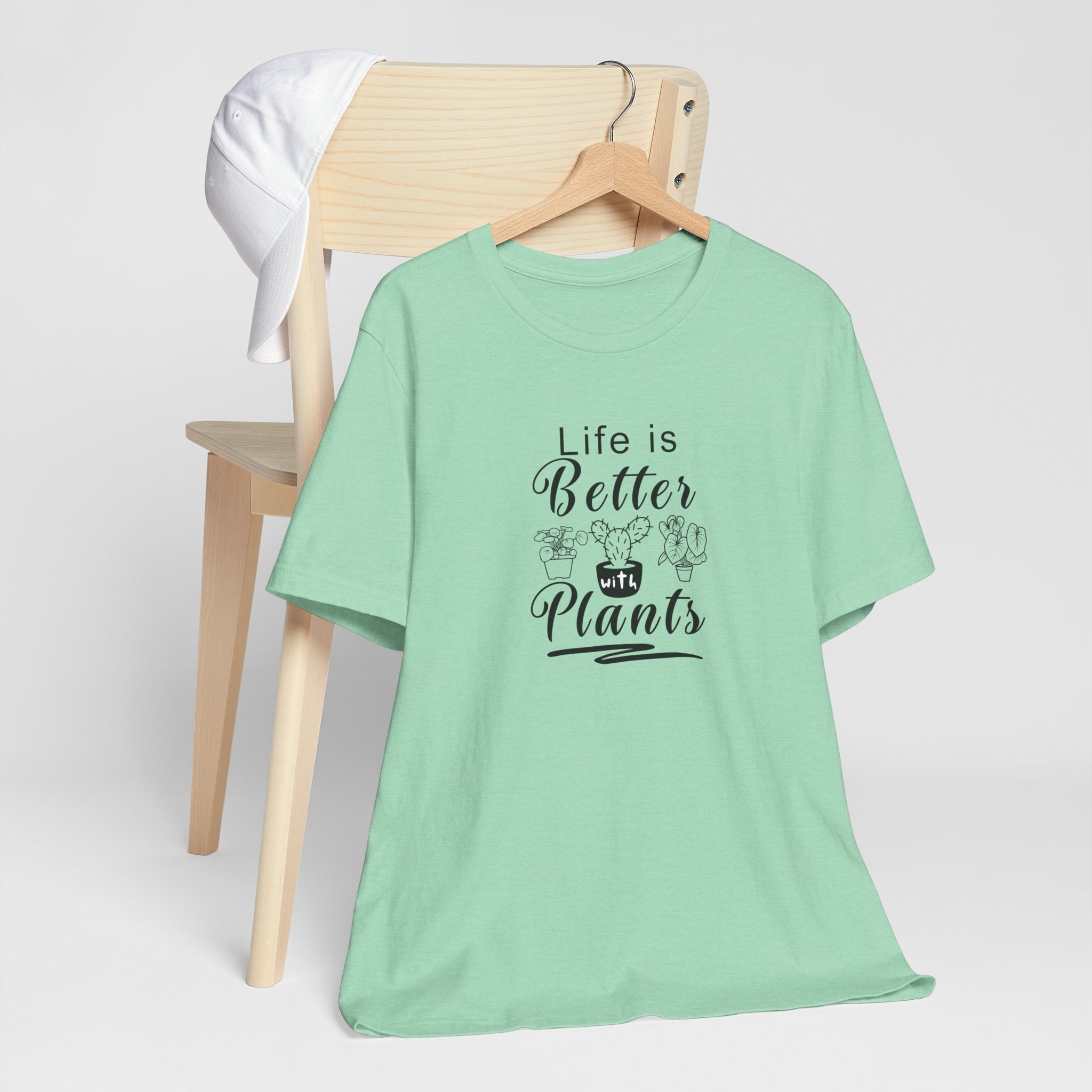 A picture of a hanging shirt in a heather mint color.  The tee shirt has text that says "Life is Better with Plants" printed on the front.