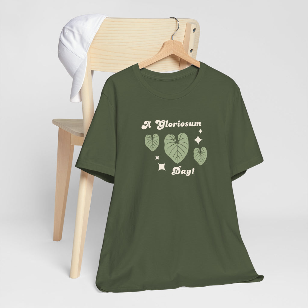 A military green colored top with text that says "A gloriosum day!"  The shirt design also has leaves from the philodendron gloriosum plant. 
