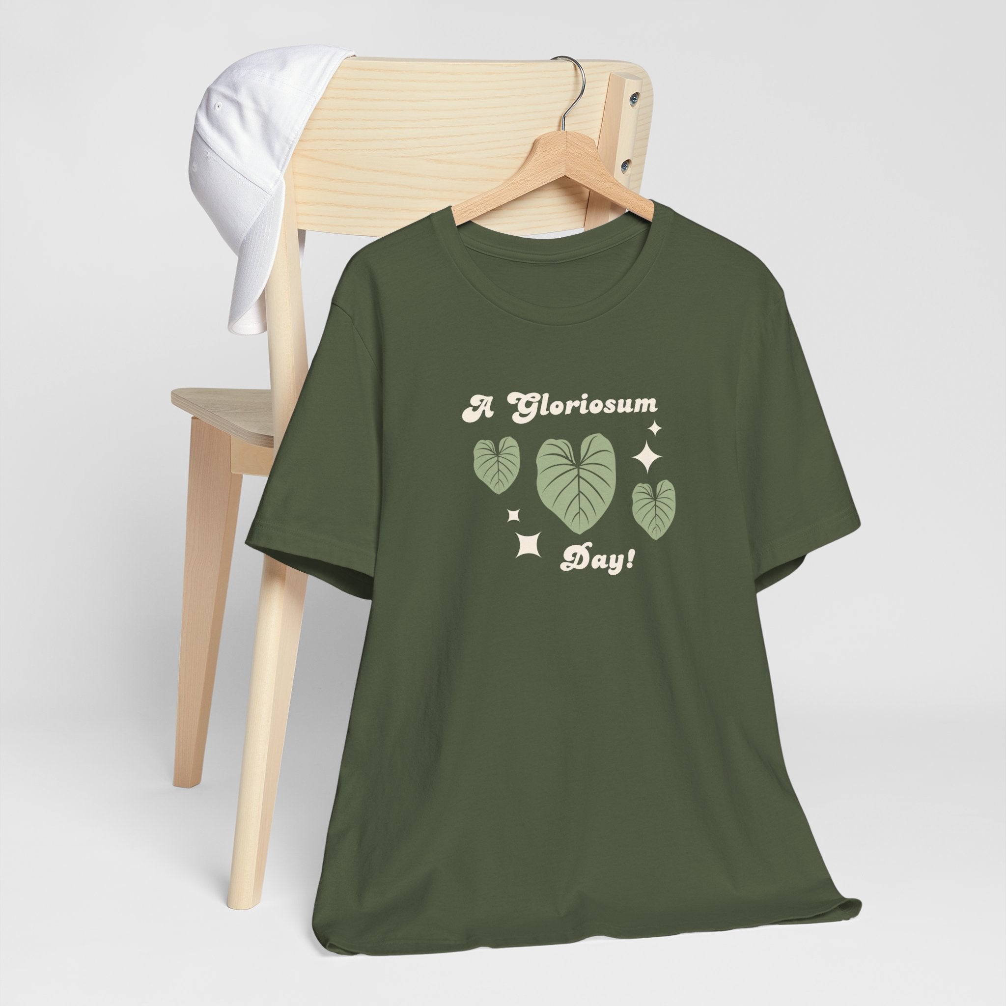 A military green colored top with text that says "A gloriosum day!"  The shirt design also has leaves from the philodendron gloriosum plant. 