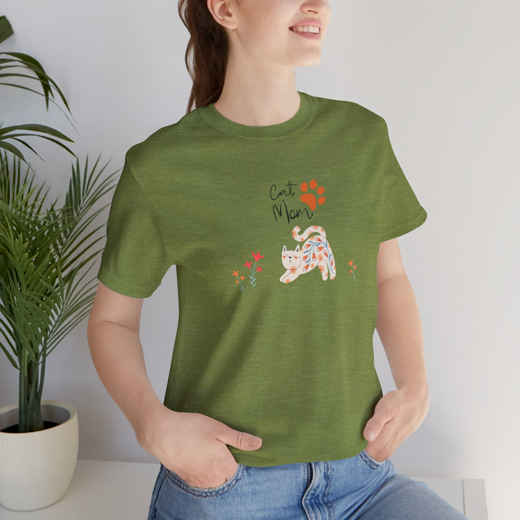 A person wearing a heather green t-shirt with the words "cat mom," a floral cat, and some flowers printed on the front of the shirt.