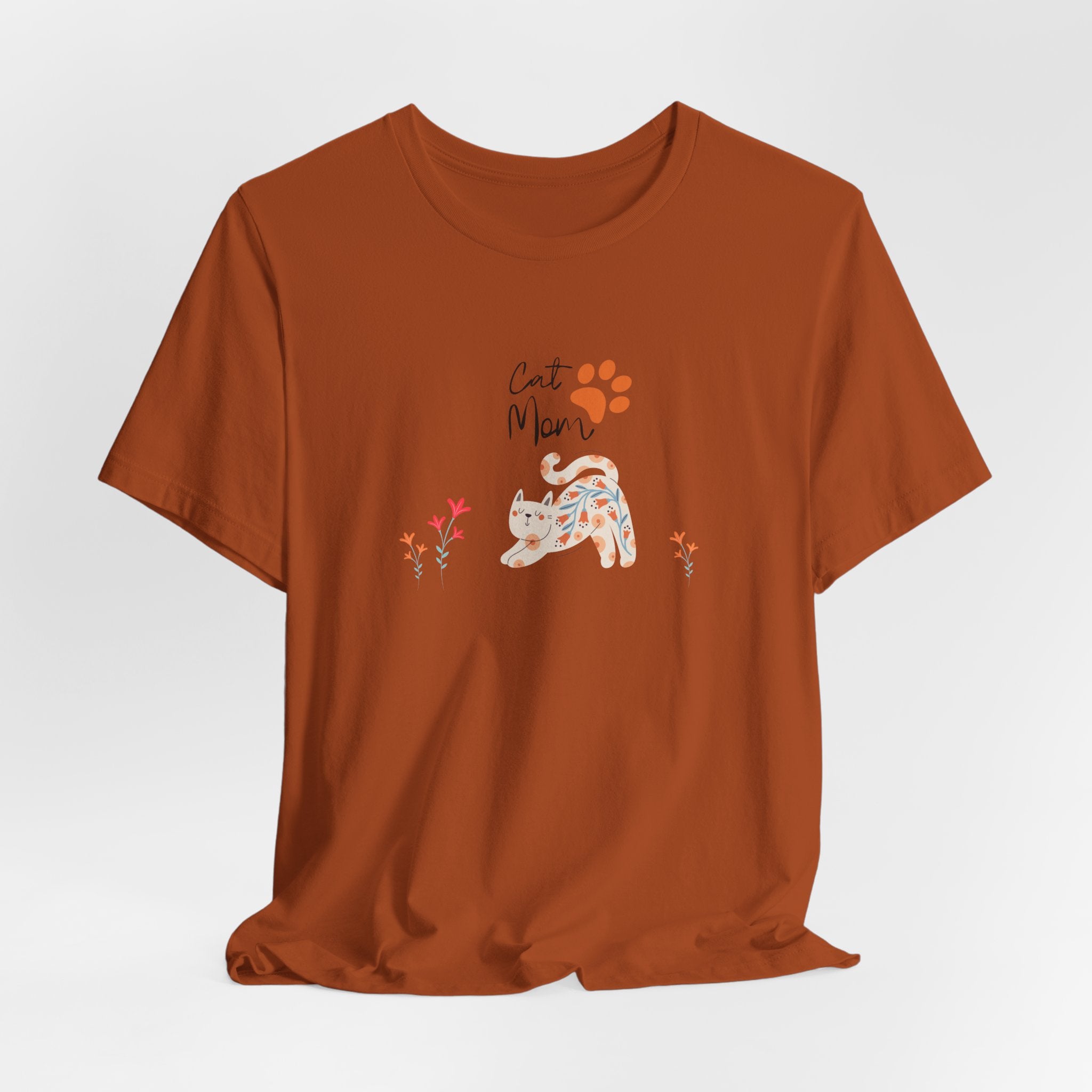 An autumn colored t-shirt with text that says "Cat Mom."  There is also a cat print, a floral cat, and flowers around the cat design. 