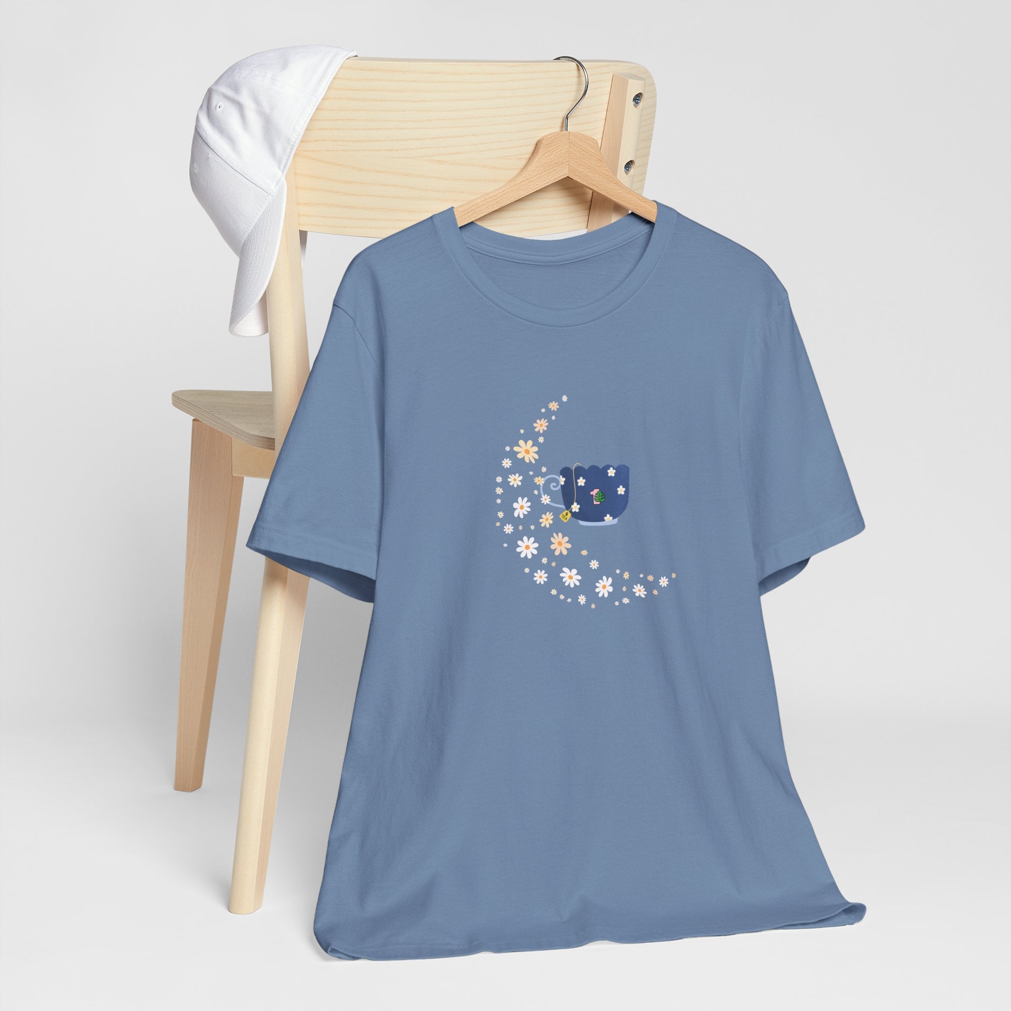 A steel blue colored tee-shirt featuring a floral moon and a teacup design.  It has a crew neck and short sleeves.  