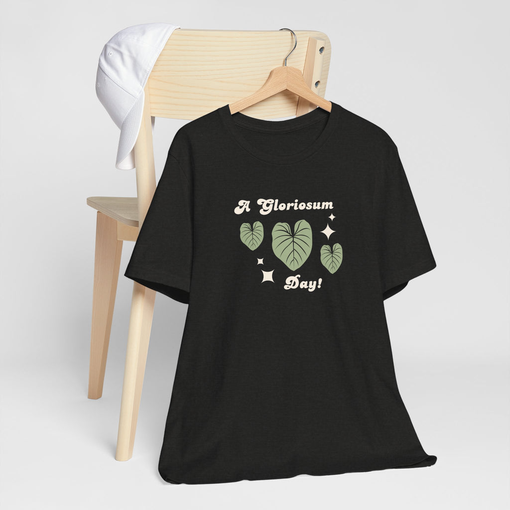 A cute plat t-shirt with a philodendron gloriosum house plant design and text that says "A gloriosum Day!" An excellent gift for plant lovers, plant collectors, and plant enthusiasts. Great as a birthday gift. This folded t-shirt comes in a black Heather color.