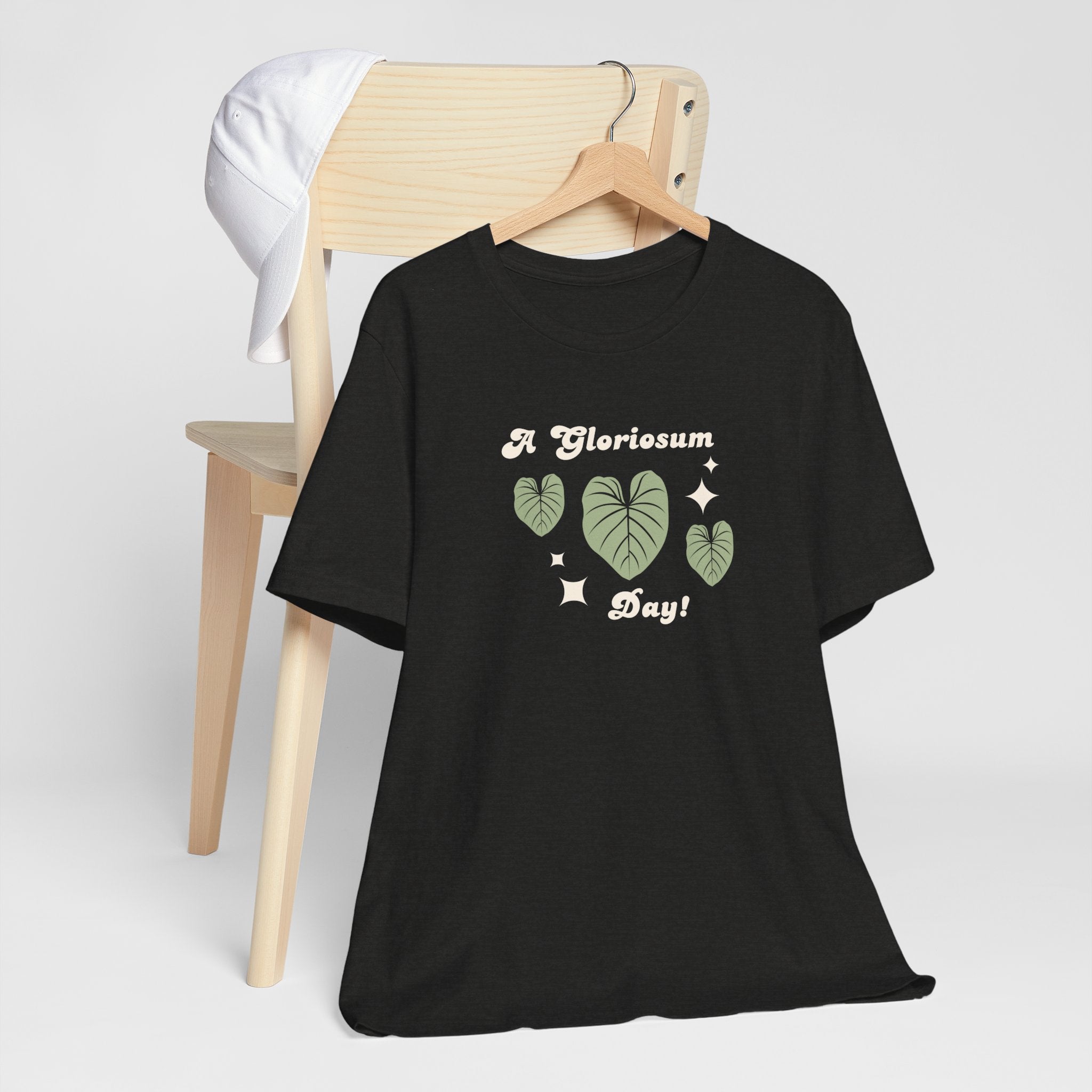 A cute plat t-shirt with a philodendron gloriosum house plant design and text that says "A gloriosum Day!" An excellent gift for plant lovers, plant collectors, and plant enthusiasts. Great as a birthday gift. This folded t-shirt comes in a black Heather color.
