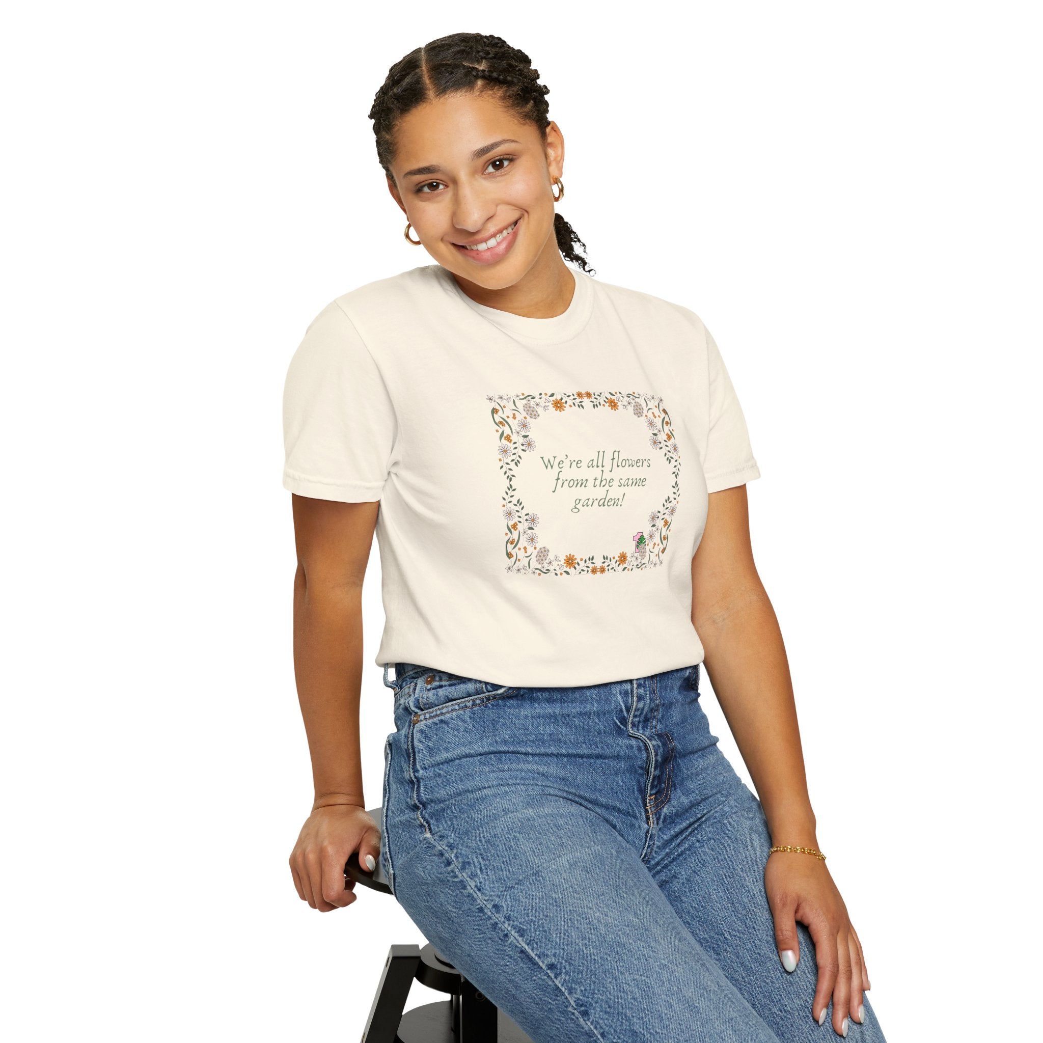 A person wearing a tee shirt with a sentence that says "we're all flowers from the same garden!" 