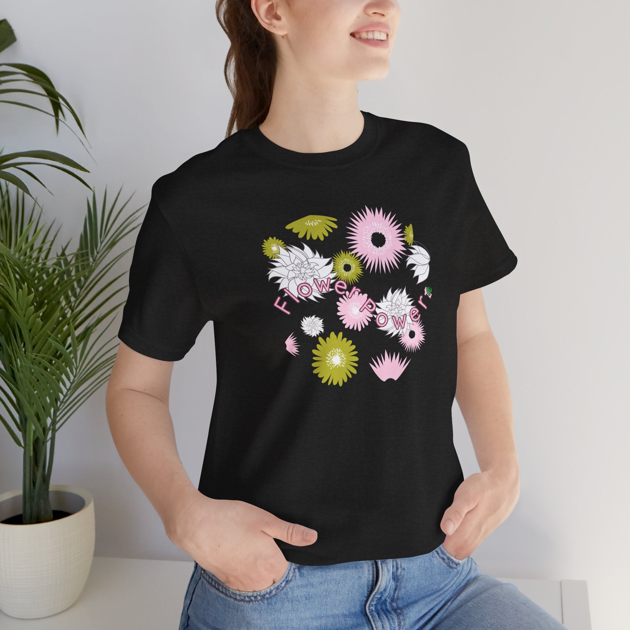 A person wearing a black color tee shirt with the words flower power in pink.  There are also pink, white, and green flowers printed on the shirt.