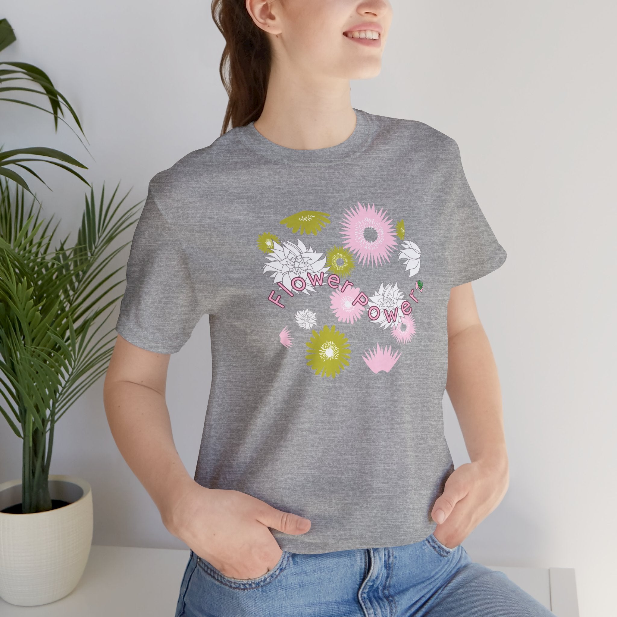A person wearing an athletic heather color tee shirt with the words flower power in pink.  There are also pink, white, and green flowers printed on the shirt.