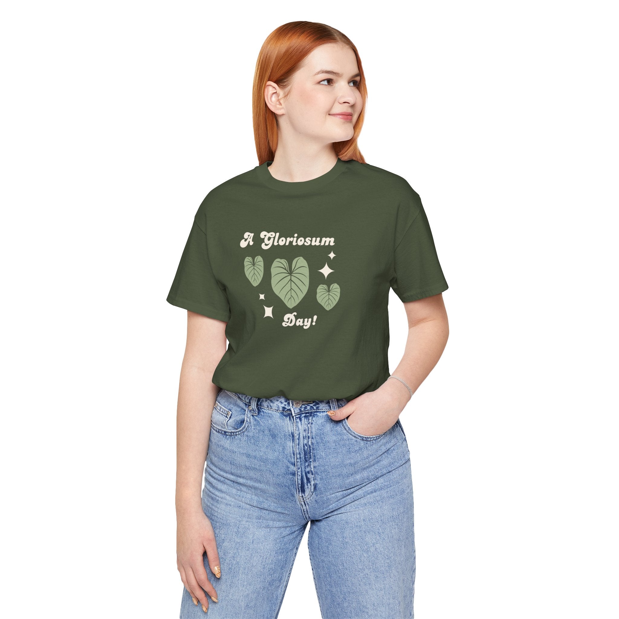 A student wearing a military green t-shirt with text that says "A gloriosum day!"  The shirt design also has leaves from the philodendron gloriosum plant. An excellent gift for plant collectors and houseplant enthusiasts. 